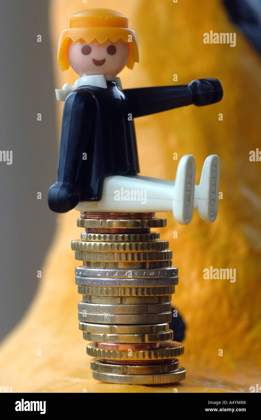 Auf einem Stapel von Euro-Münzen sitzend Figur (Playmobil). Stockfoto