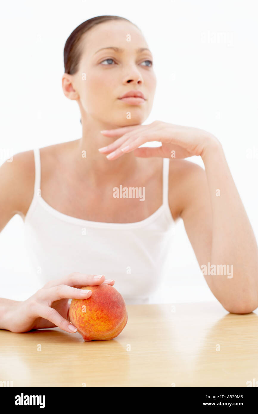Eine junge Frau mit einem Pfirsich wegschauen Stockfoto