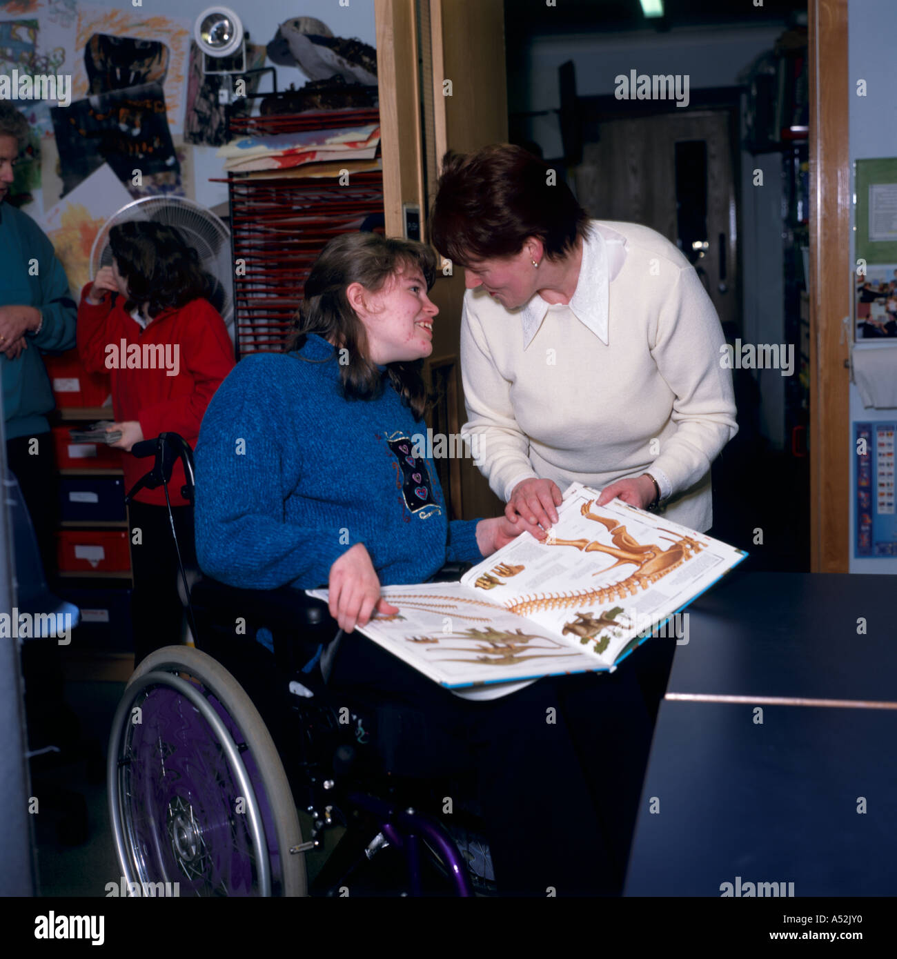 Behindertes Mädchen im Rollstuhl und Lehrer im Klassenzimmer der Schule, lesen Stockfoto