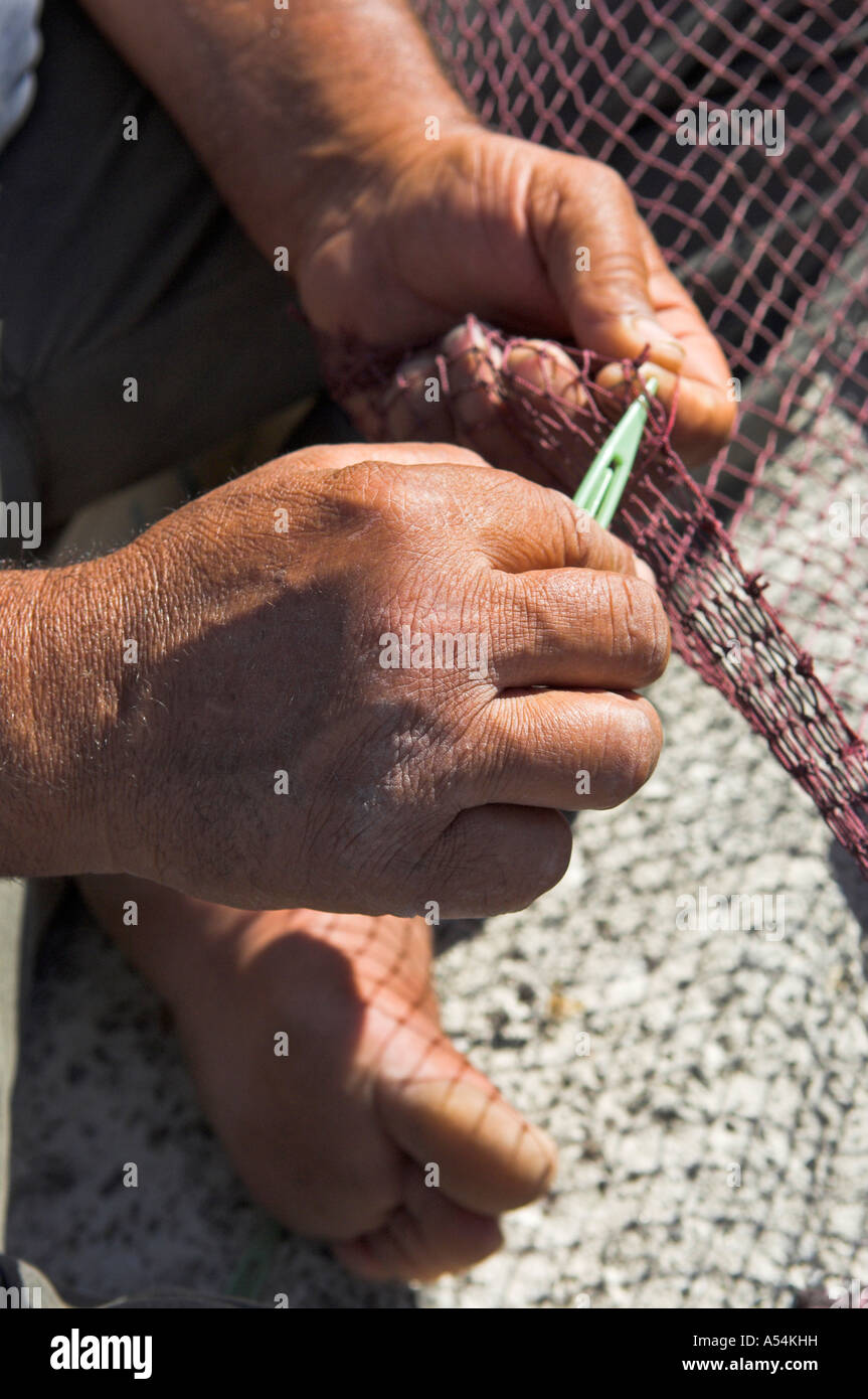 Nahaufnahme von Fischer s Hände und Finger Reparatur Netze am Kai in Griechenland Stockfoto