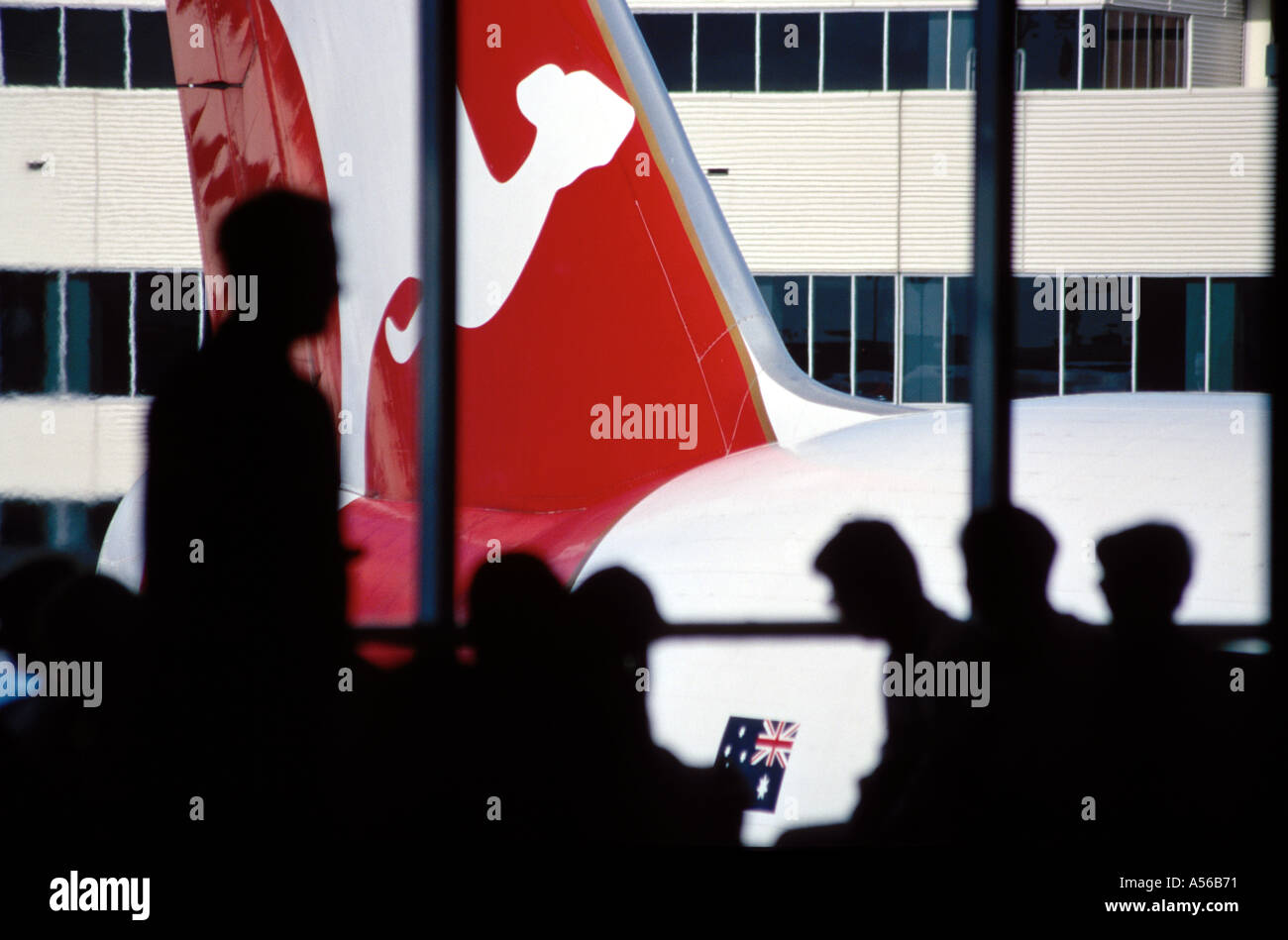 Schwanzflosse von Qantas-Flugzeug gesehen durch Fenster von Qantas Lounge Flughafen Sydney Australien Menschen Silhouette im Vordergrund Stockfoto