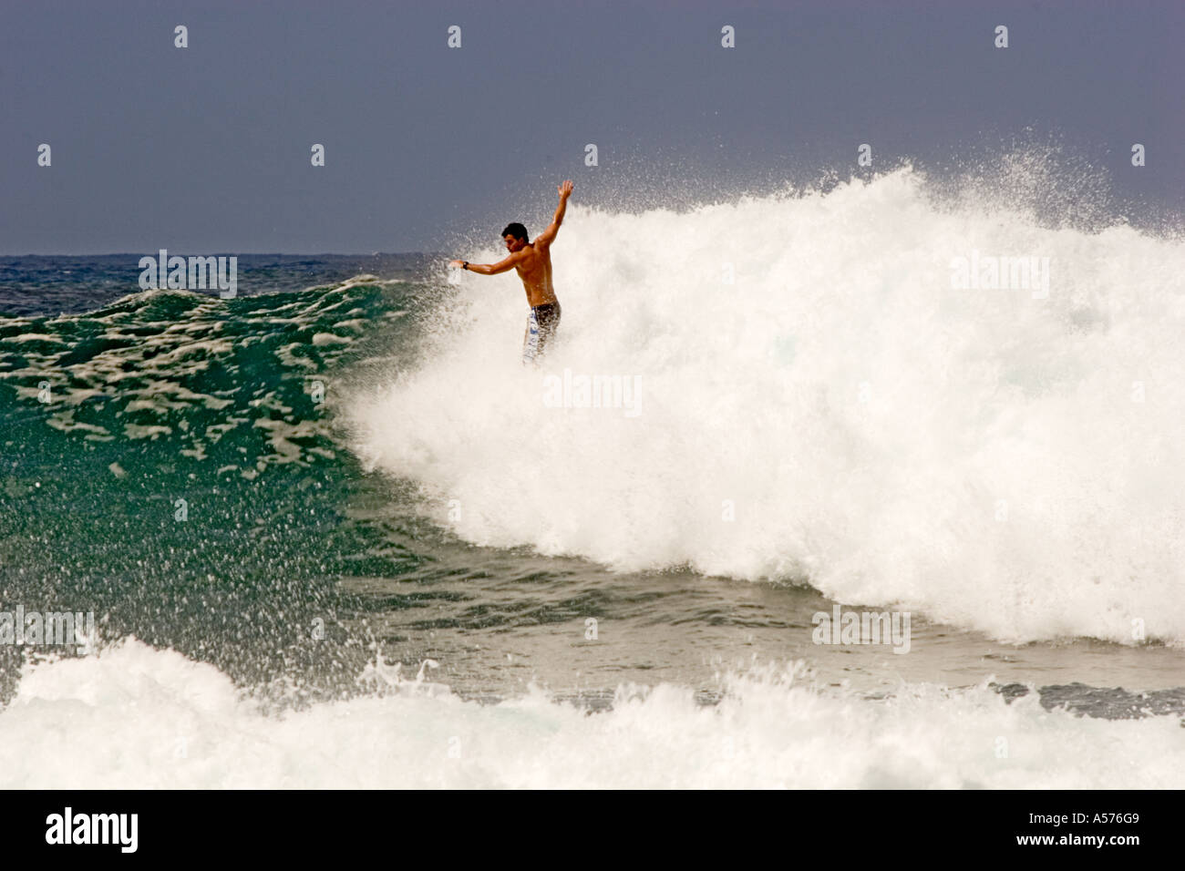 Surfer-Guthaben auf seinem Brett, während im Spray verschlungen Stockfoto