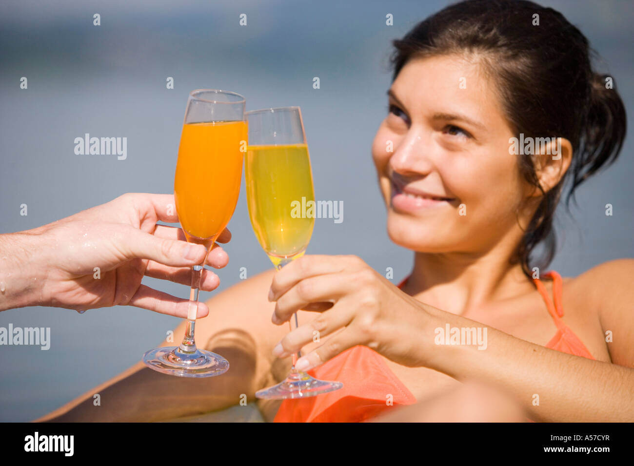 Junge Frau, die Gläser klirren Stockfoto