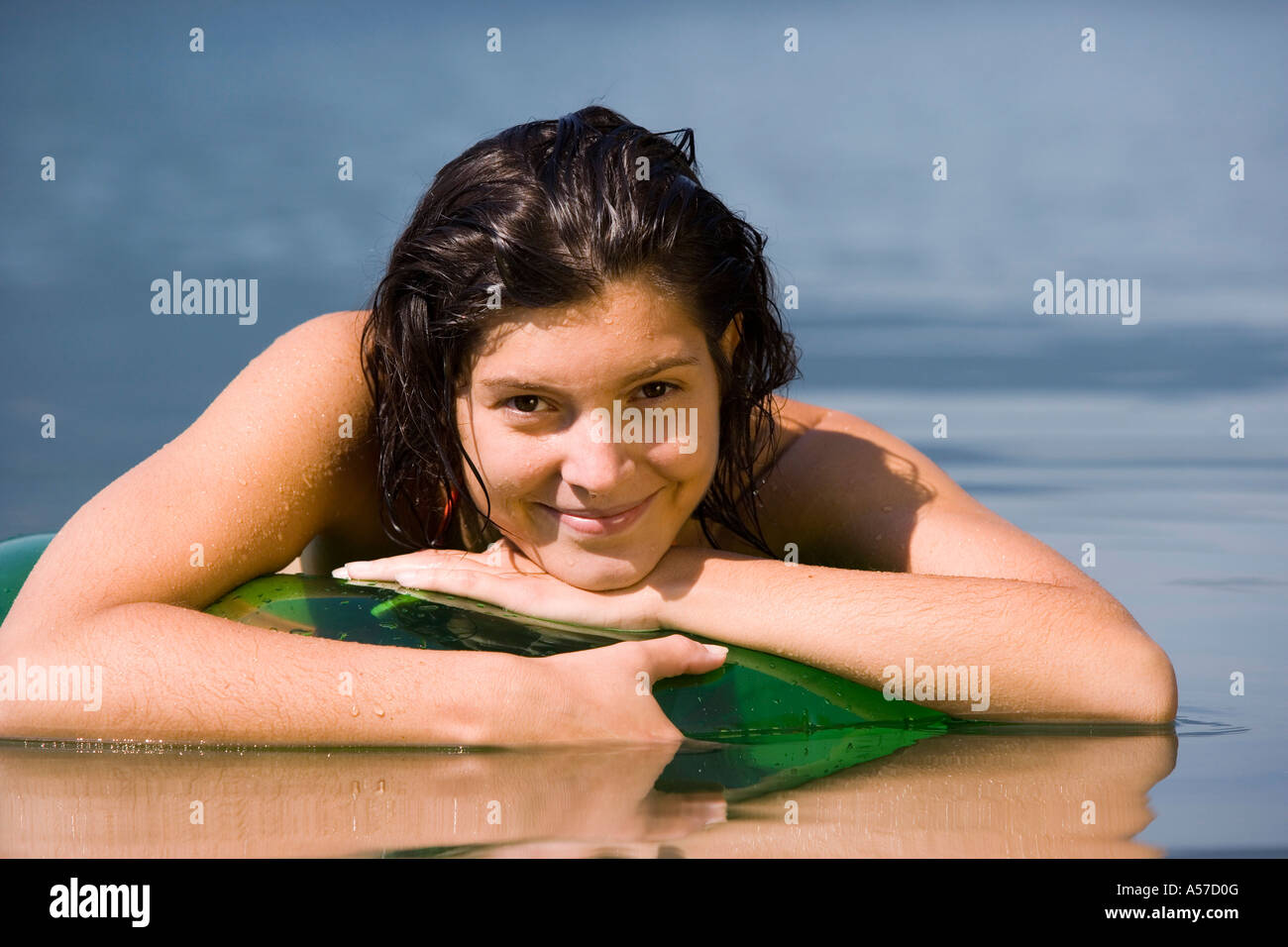 Junge Frau liegt auf schwimmenden Reifen in See Stockfoto