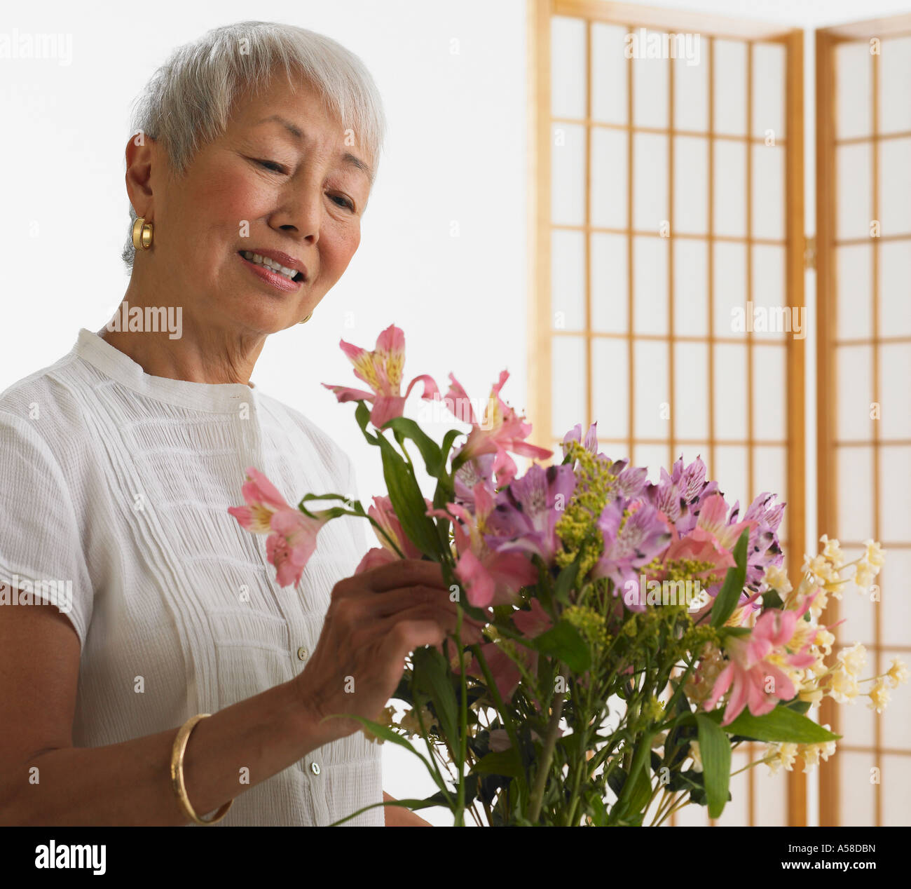 Hochrangige asiatische Frau arrangieren Blumen im Haus Stockfoto