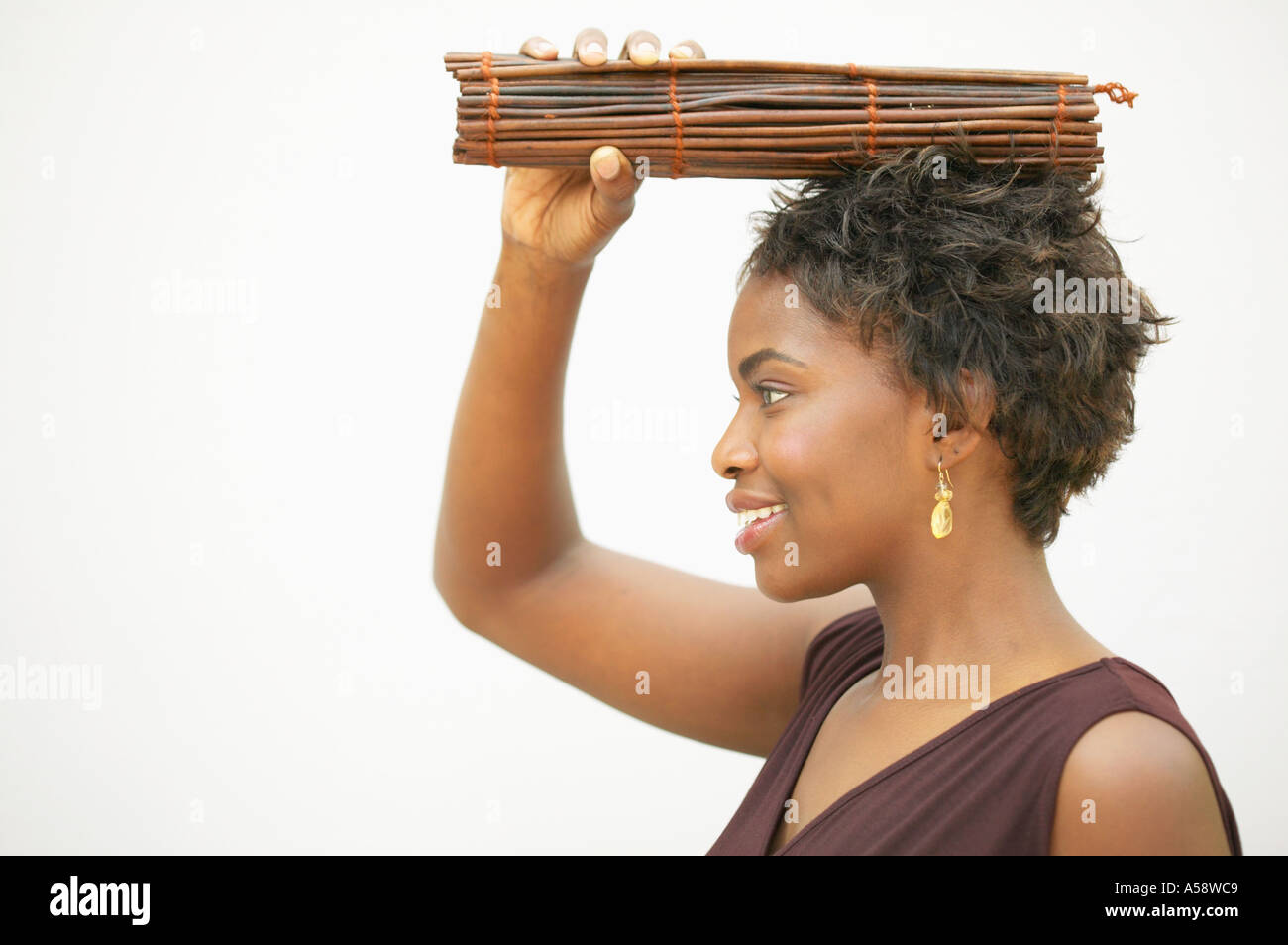 Profil von Frau hält Bündel von Zweigen auf Kopf Stockfoto