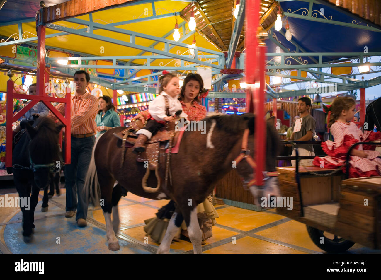 Kleinkinder auf Fairground Karussell mit Leben Ponys, Fuengirola Feria, Costa Del Sol, Spanien, Europa, Stockfoto