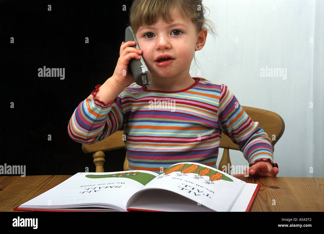 3 - Jahre altes Mädchen im Gespräch mit ihrer Freundin auf ein schnurloses Telefon in ihrem Haus Suffolk. Stockfoto