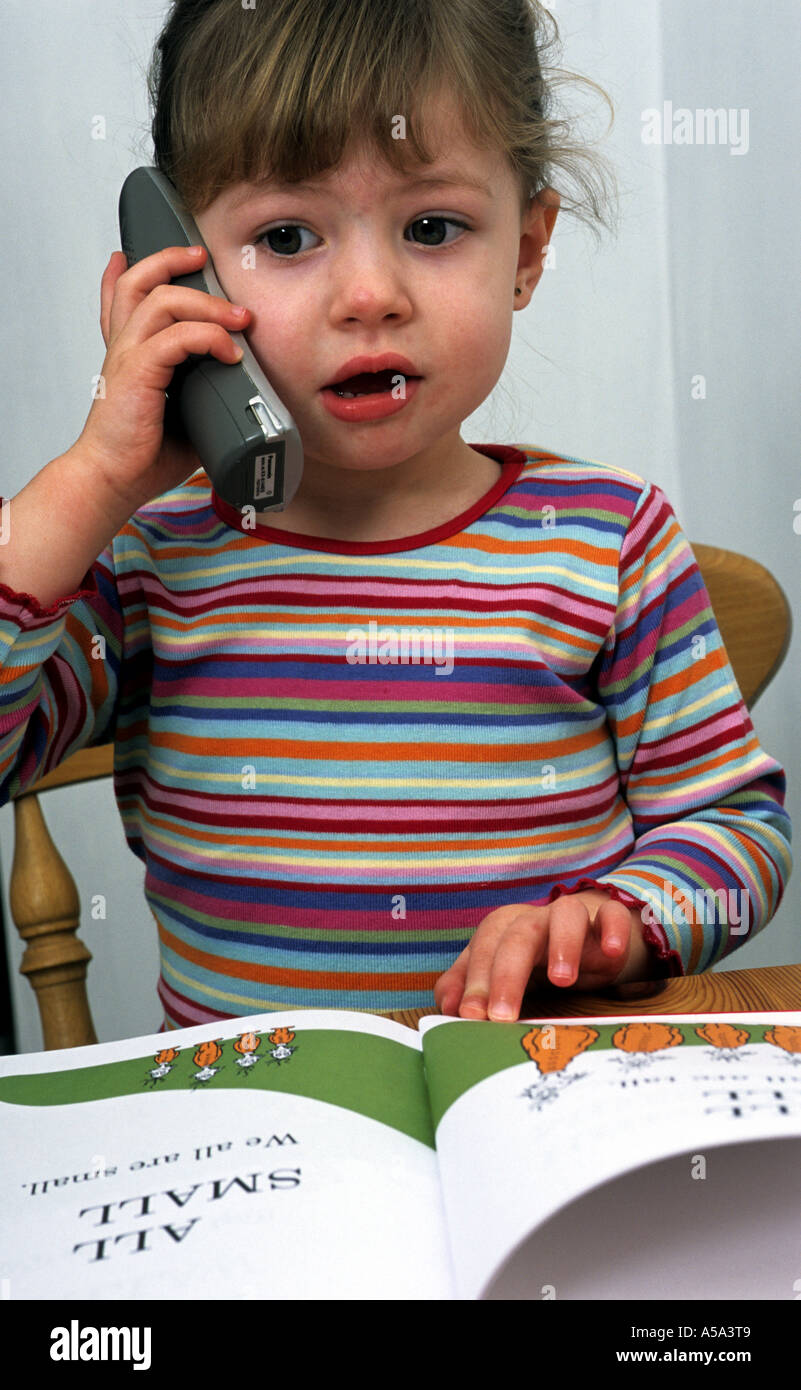 3 - Jahre altes Mädchen im Gespräch mit ihrer Freundin auf ein schnurloses Telefon in ihrem Haus Suffolk. Stockfoto