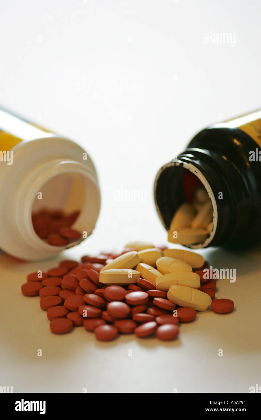 Bunte Generika Tabletten Kapseln Medizin Spill aus 2 Container auf einem weißen Hintergrund Stockfoto
