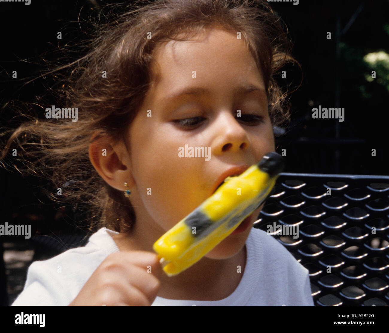 Eis am Stiel. Ein junges Mädchen, das an einem heißen Sommertag im Park ein Eis am Stiel leckt. USA Stockfoto