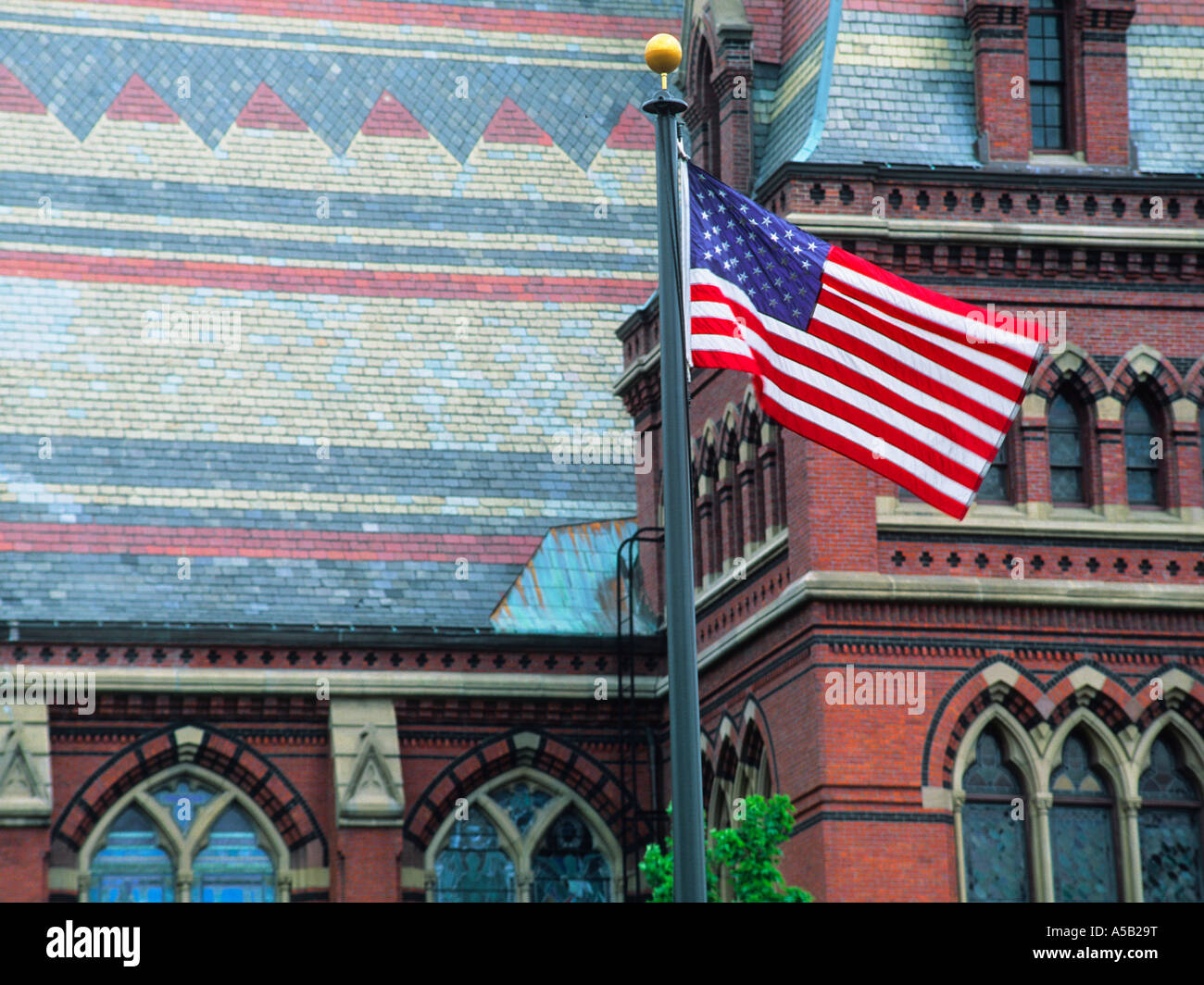 Memorial Hall Harvard University, amerikanische Flagge auf einem Fahnenmast. Cambridge Mass Massachusetts, USA. Hohe viktorianische Architektur im gotischen Stil Stockfoto