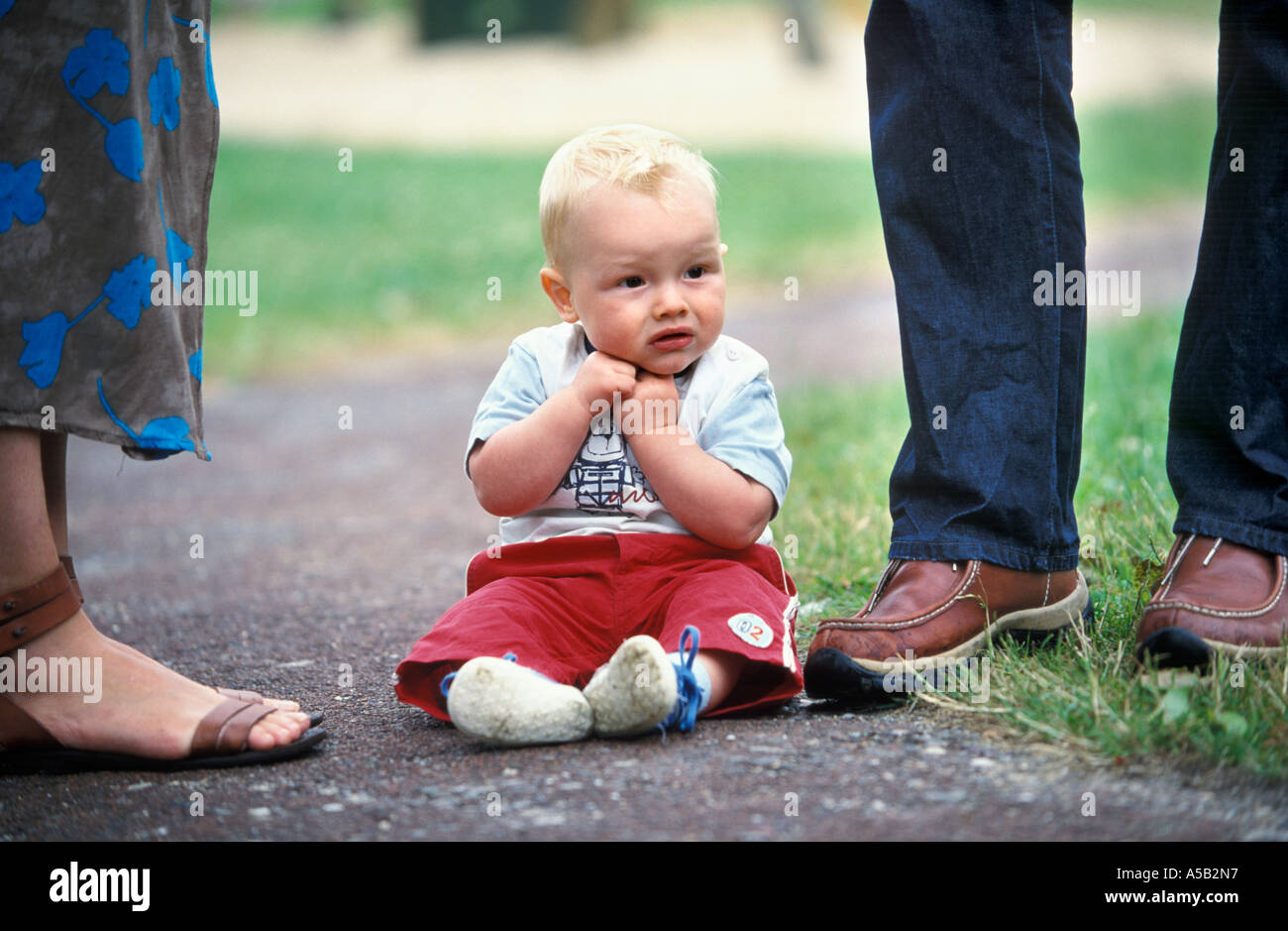 Kleine Baby Junge sitzt vor seiner Eltern Beine Stockfoto