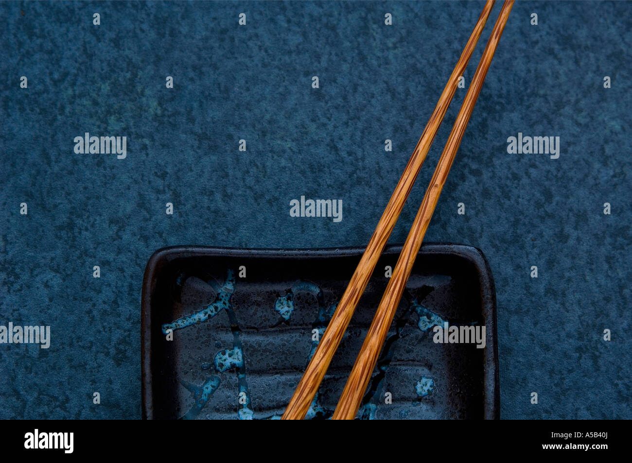 Hölzerne Stäbchen mit Gericht auf blauem Hintergrund. Stockfoto