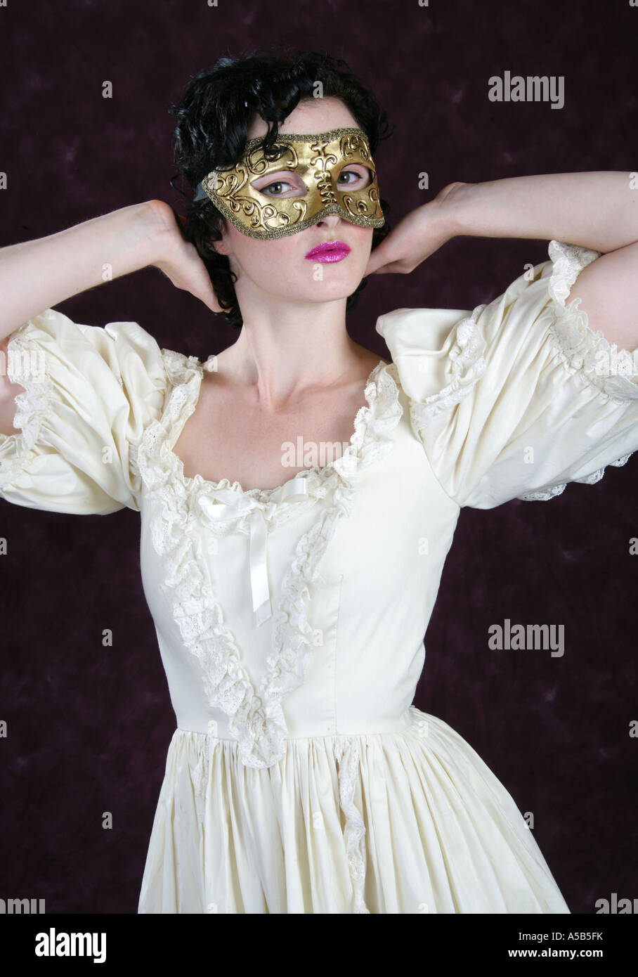 Porträt einer jungen Frau trug eine goldene Maske und einem cremefarbenen Kleid Stockfoto
