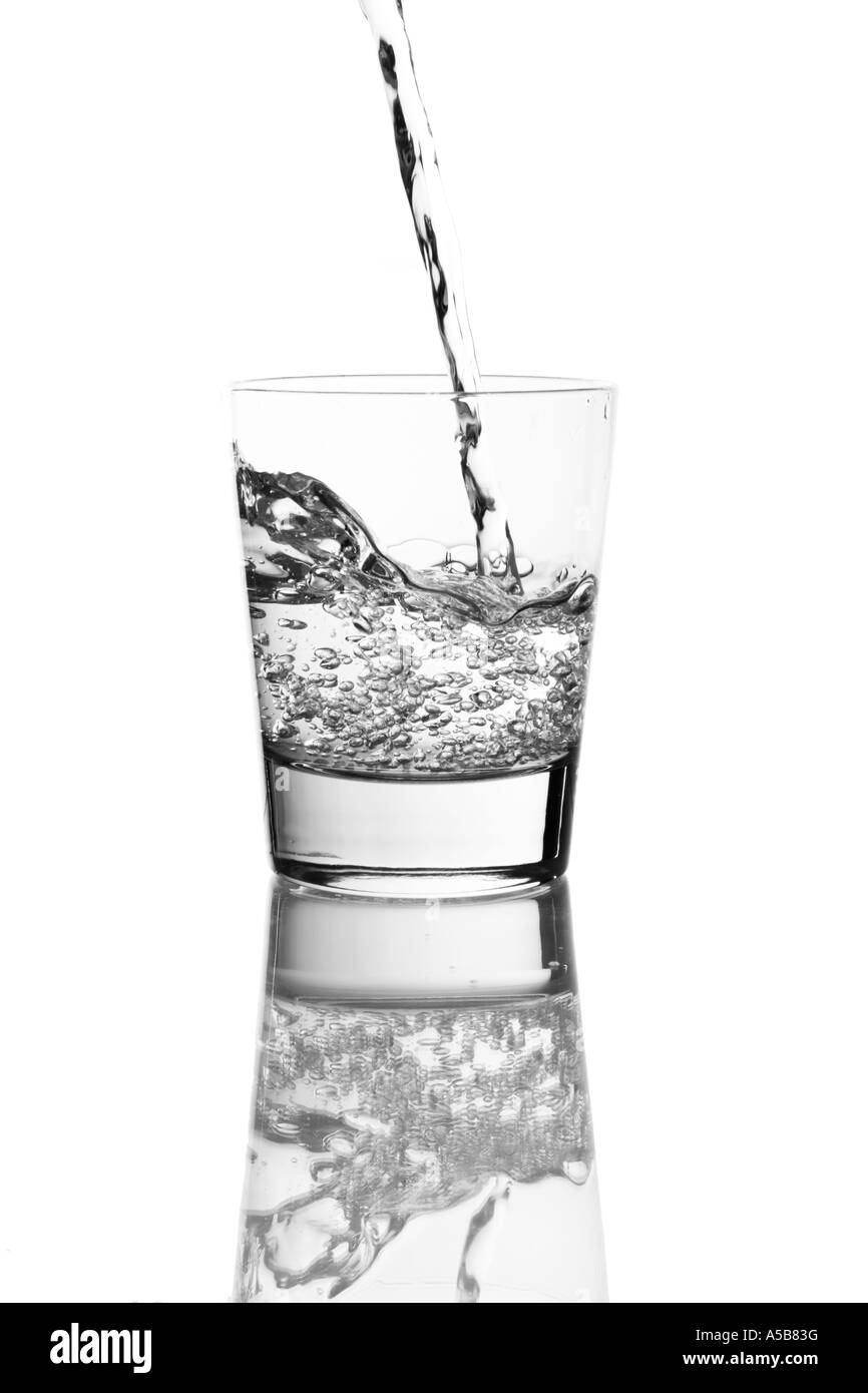 Gießen ein Glas Wasser auf eine reflektierende Tischplatte Stockfoto