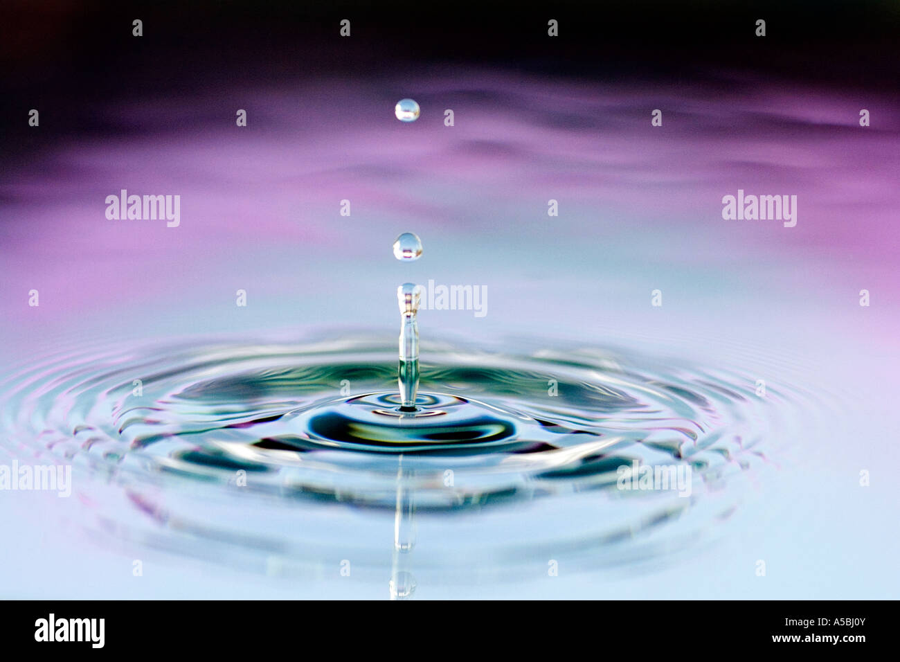 Gefärbtes Wassertropfen und Welligkeit. Wasser auf eine Platte Spiegel reflektierte Farbe Hintergrund. Stockfoto