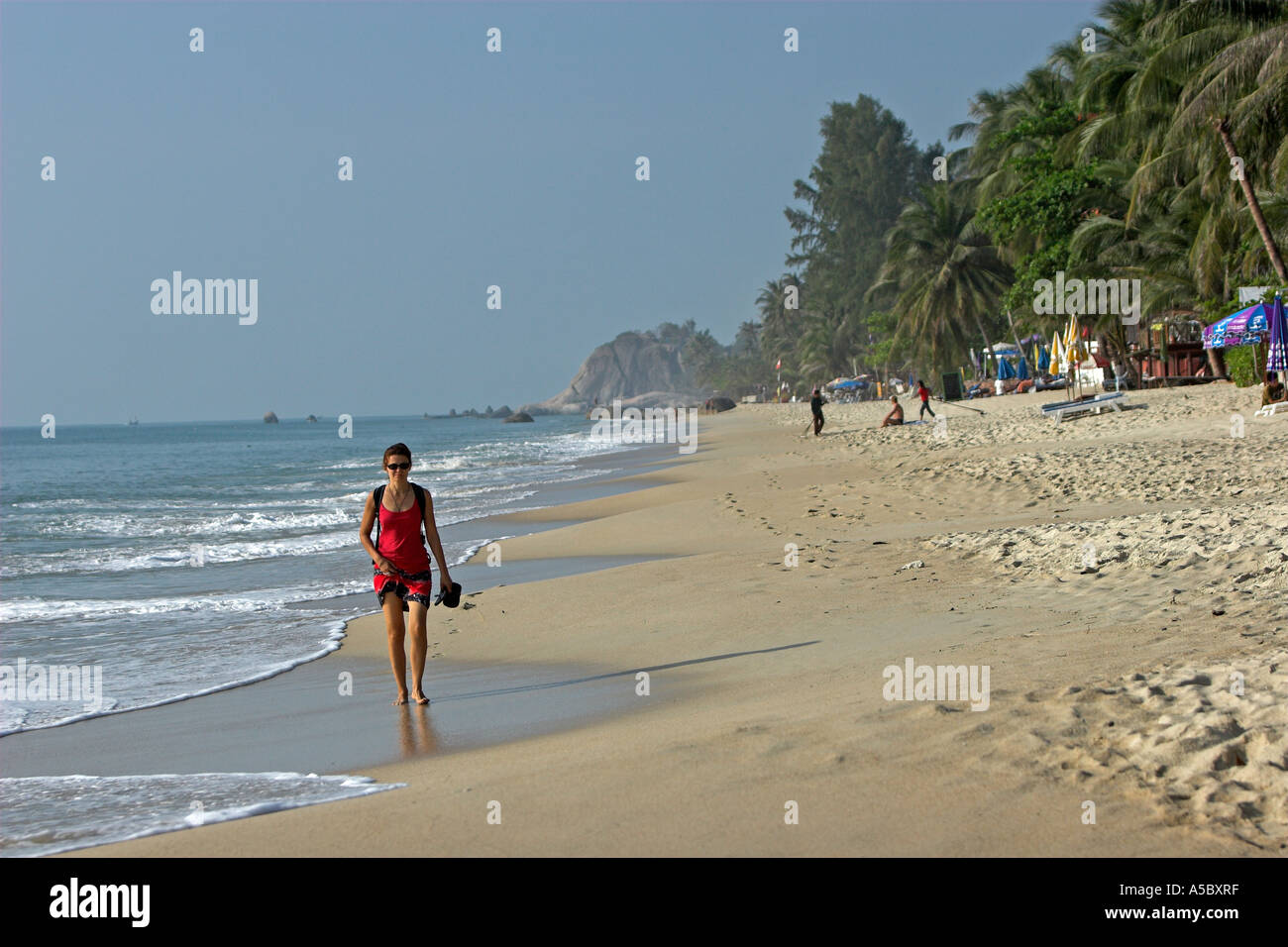 Rotes Kleid Frau geht barfuß in Wellen am frühen Morgen Lamai Strand Ko Samui Insel Thailand Stockfoto