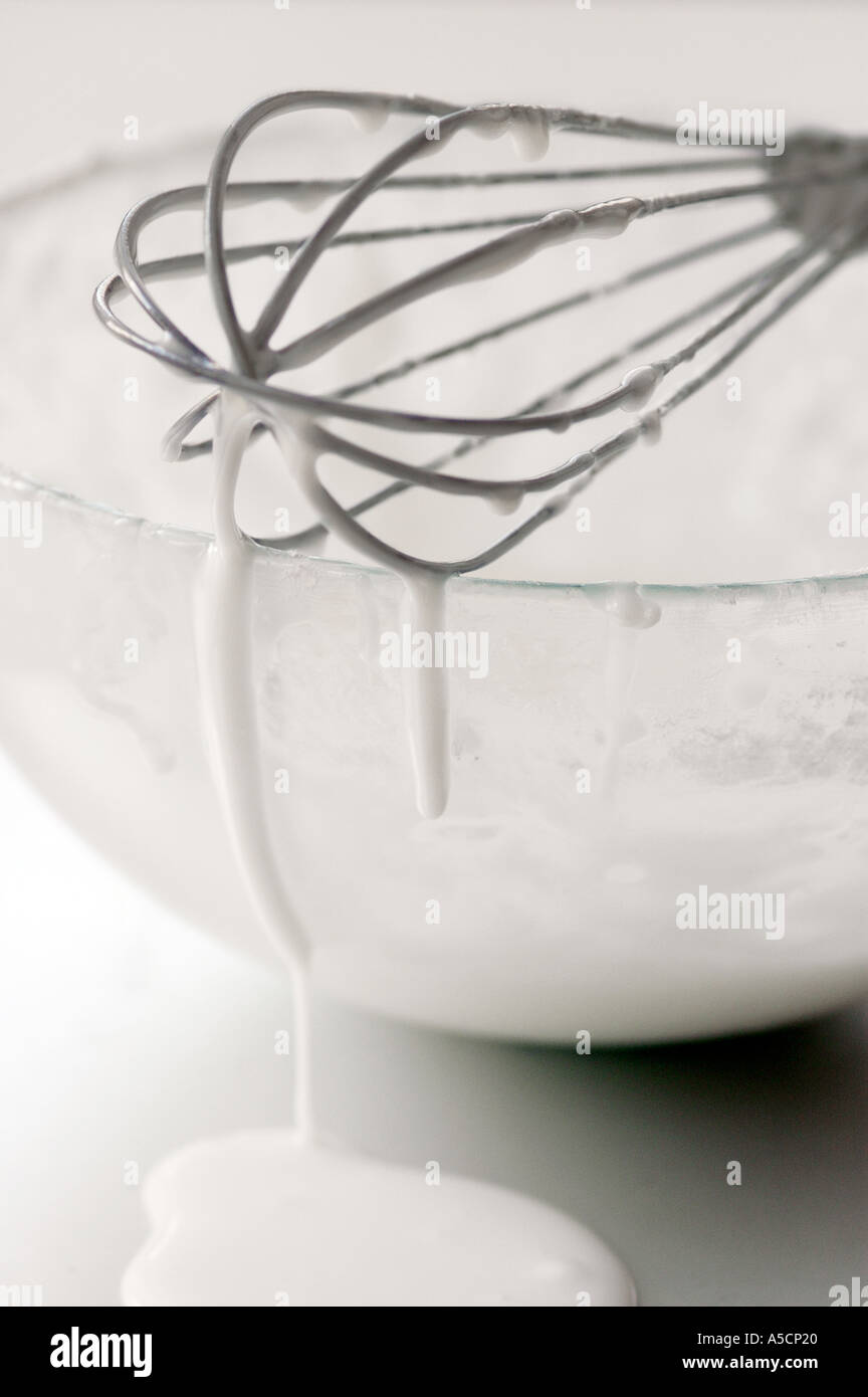 Schüssel mit weißem Zuckerguss mit tropfenden Schneebesen Stockfoto