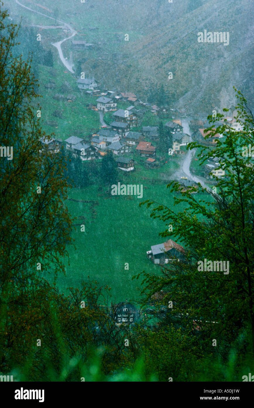 Nebligen Graupel verschneiten Blick auf ländliche Dorf tief im Tal, Sommer, Schweizer Alpen, Schweiz Stockfoto