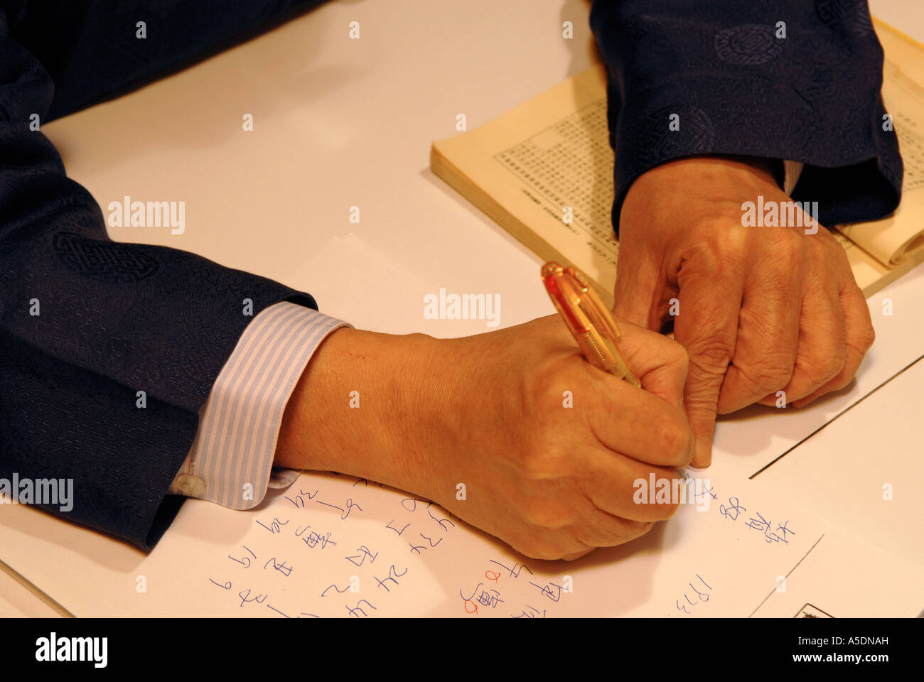 Menschen schreiben mit Stift im chinesischen Text auf weißem Papier Stockfoto Menschen schreiben mit Stift im chinesischen Text auf weißem Papier Stockfoto