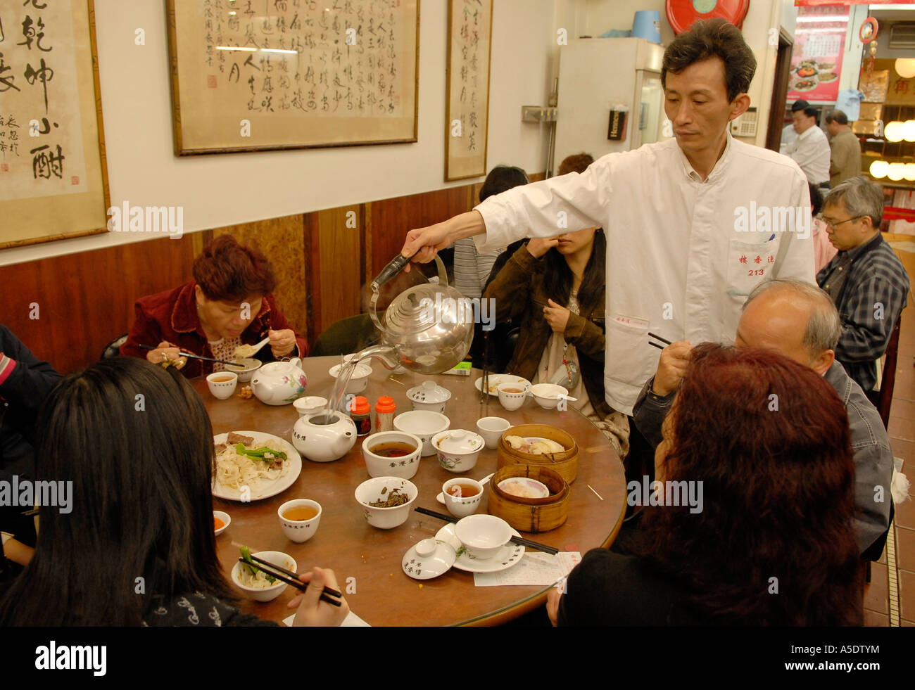 Kellner gießt Kaffee in einem traditionellen chinesischen Teehaus, die Halbinsel Kowloon. Hong Kong China Stockfoto Kellner gießt Kaffee in einem traditionellen chinesischen Teehaus, die Halbinsel Kowloon. Hong Kong China Stockfoto