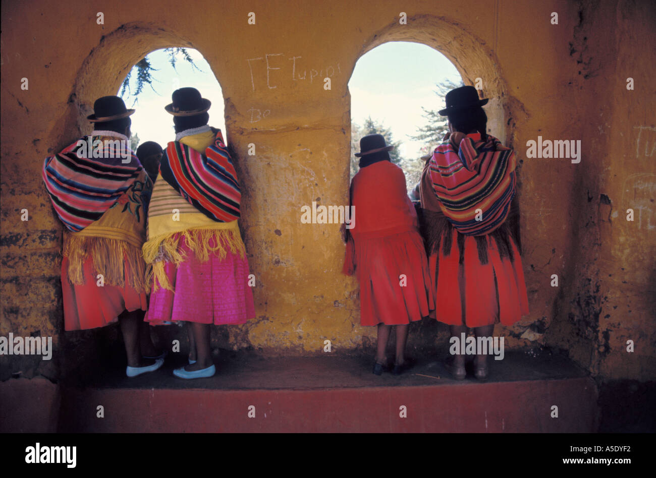 Aymara Inderinnen in ihrer Tracht, die aus einem historischen Altbau in Bolivien Stockfoto