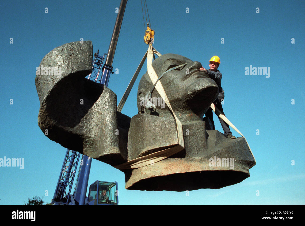 Gestürzte kommunistische Symbol zum Verkauf.  Lenins Kopf baumelt von einem Kran. Stockfoto
