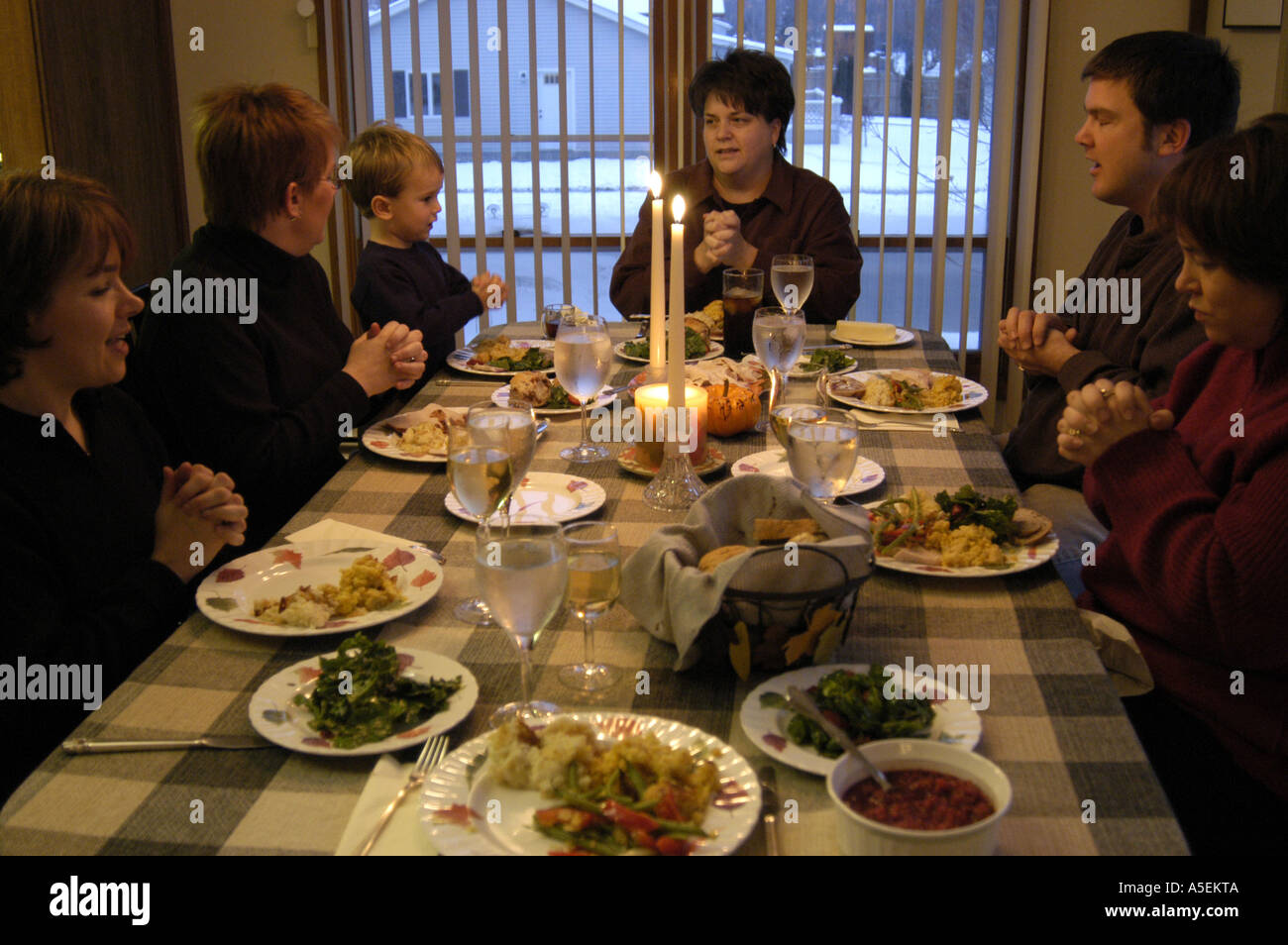 Kaukasische Familie sitzen vor Tellern essen und sagen Gebete, die Hände gefaltet vor dem Abendessen am thanksgiving Stockfoto