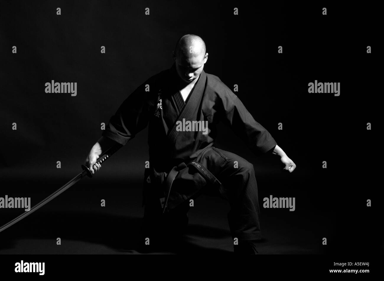 schwarzer Gürtel Karate-Lehrer mit Schwert in fertige Position mit gesenktem Kopf Stockfoto