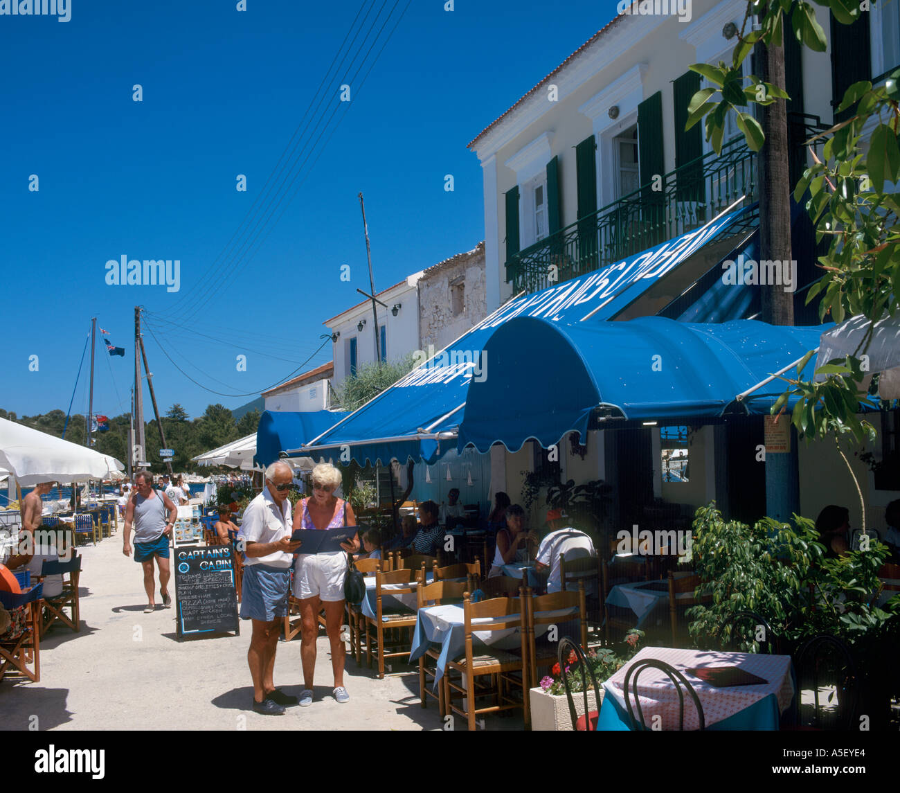 Älteres Ehepaar Blick auf eine Speisekarte außerhalb einer Taverne direkt am Meer, Fiskardo, Kefalonia, Ionische Inseln, Griechenland Stockfoto