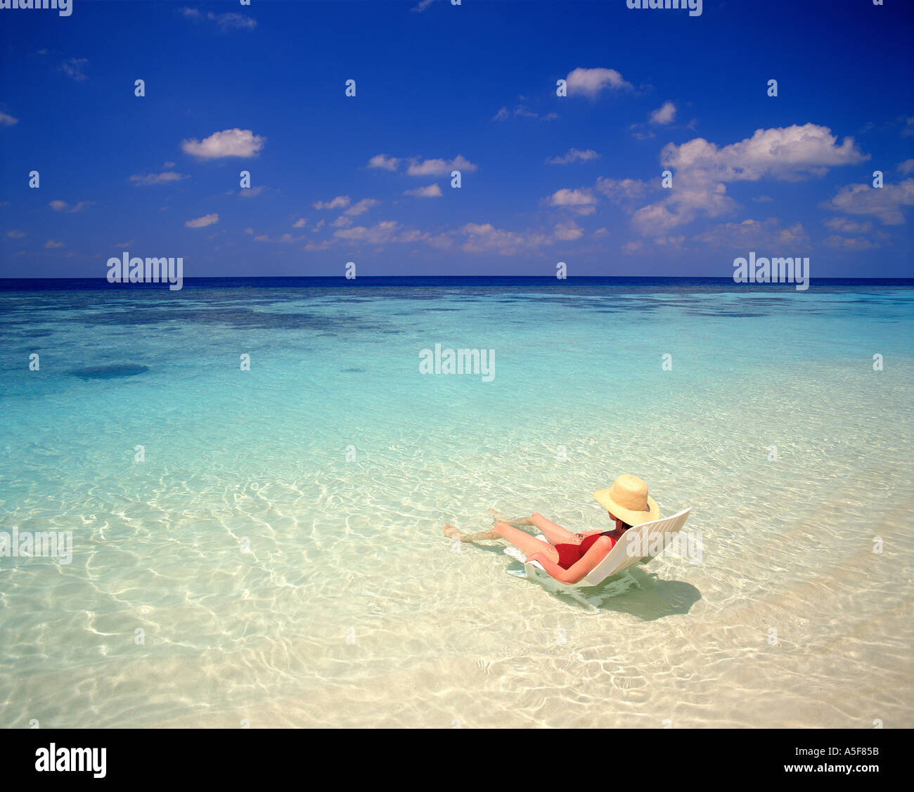 Frau sitzt auf dem Stuhl im flachen Wasser auf den Malediven  Stockfotografie - Alamy