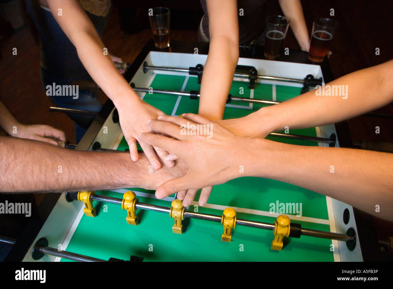 Gruppe junger Freunde umklammern übergibt sich solidarisch Tischfußball Stockfoto