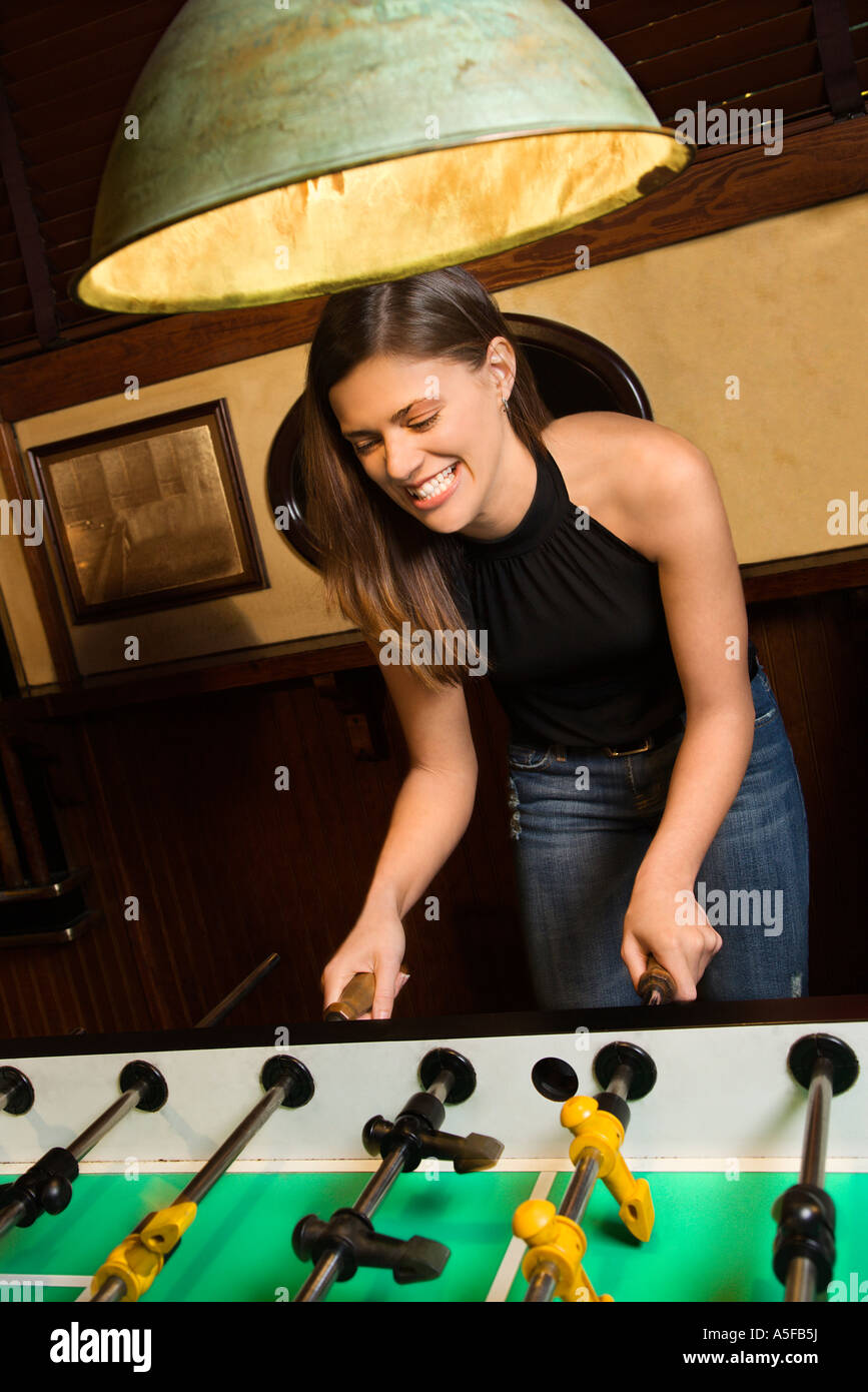 Junge Frau lächelt, beim Tischfußball Spiel im pub Stockfoto