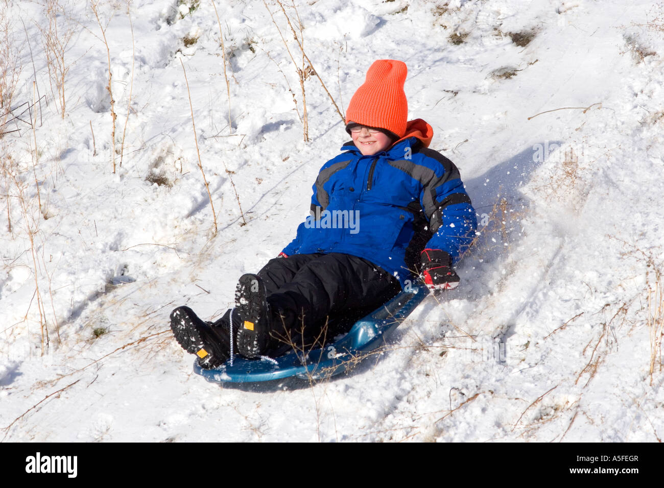 Junge einen Schnee bedeckten Hügel in Idaho hinunter rodeln Stockfoto