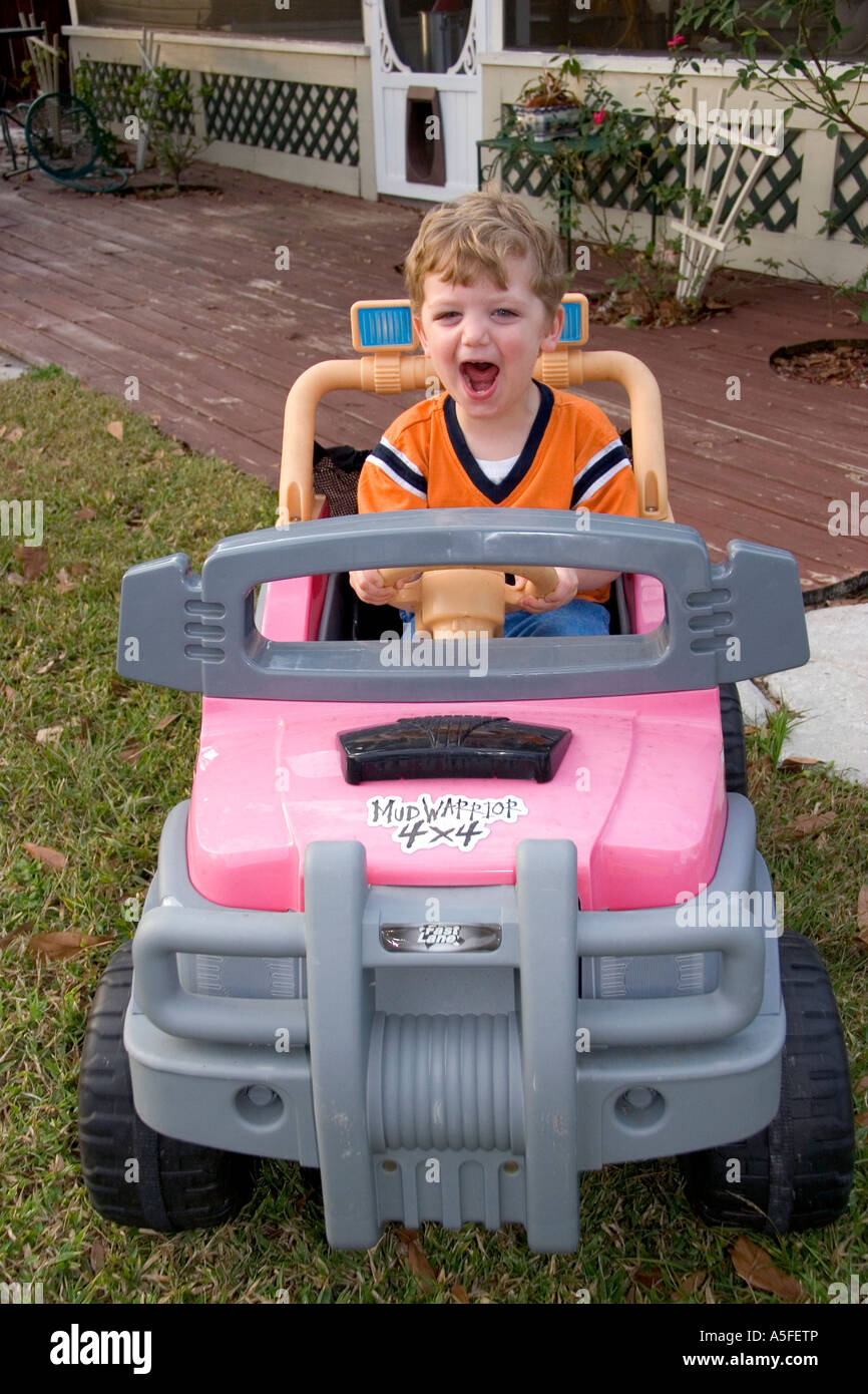 Ein drei Jahre alter Junge, der ein batteriebetriebenes Auto zu fahren Stockfoto