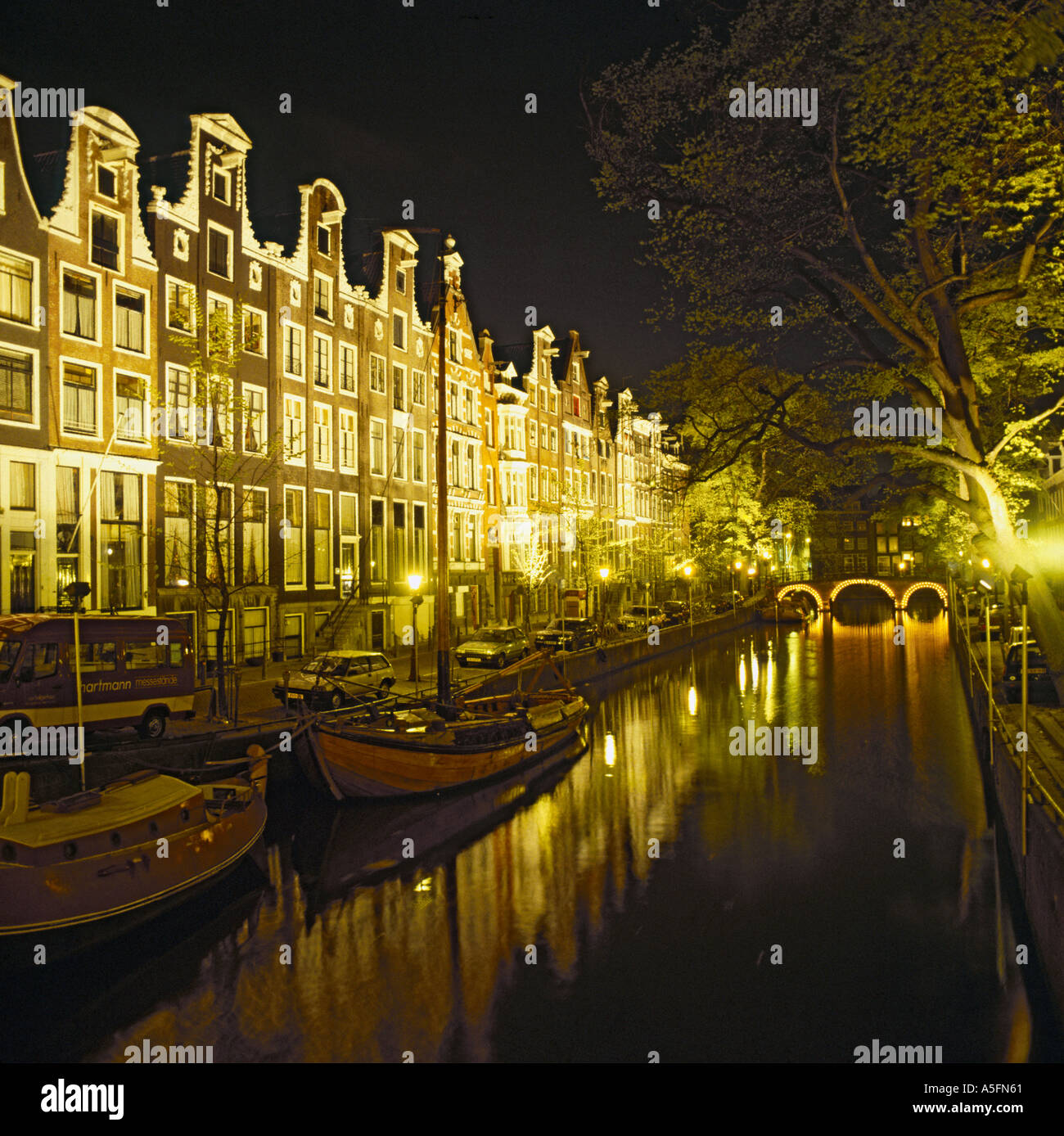 Malerische Nachtansicht der Reihe der typisch holländischen Häuser mit Fenstern hell beleuchtet neben Kanal in Amsterdam Holland Stockfoto