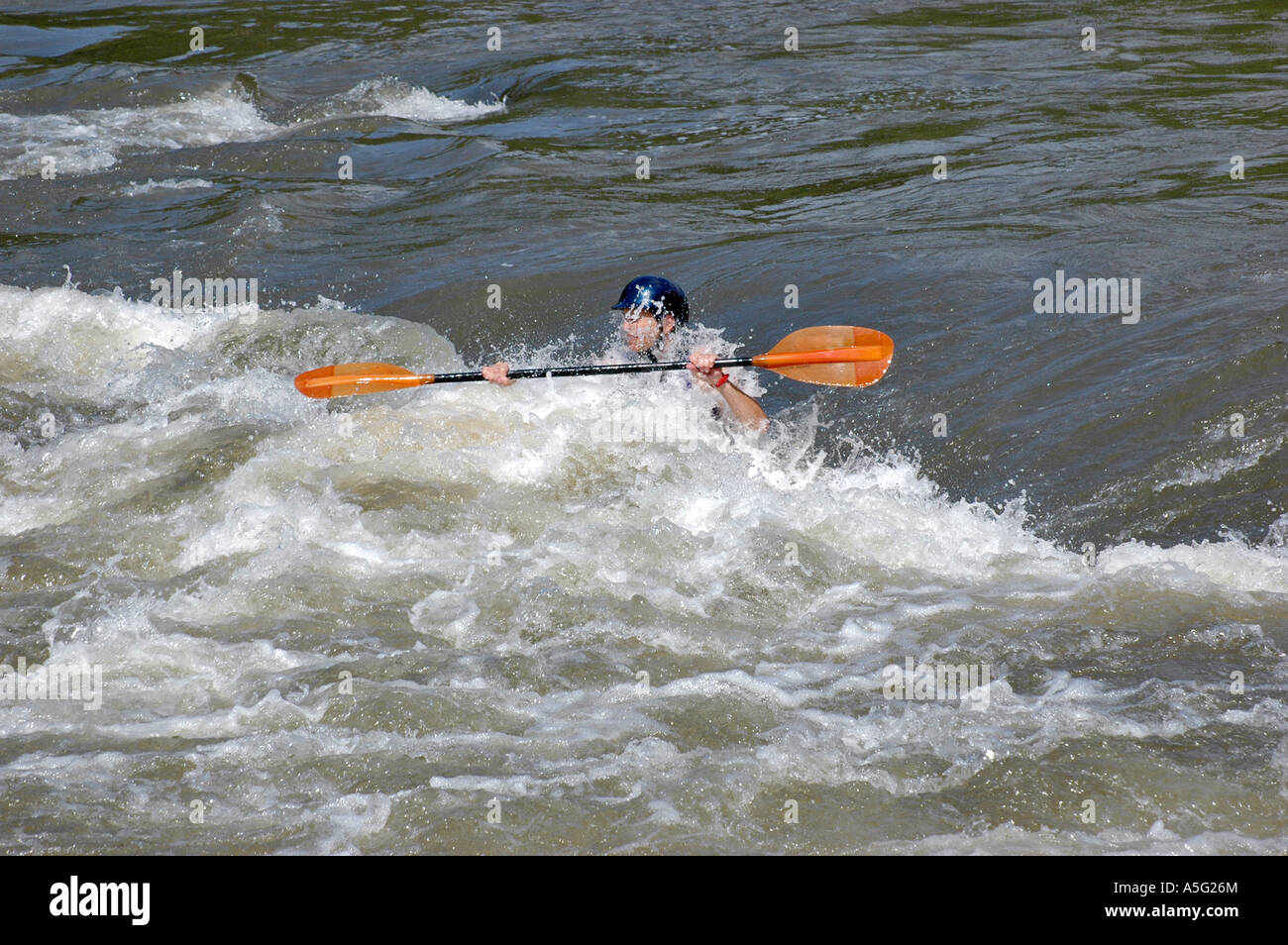 Wildwasser-Kajaker paddelt in eine Klasse III Rapid. Stockfoto