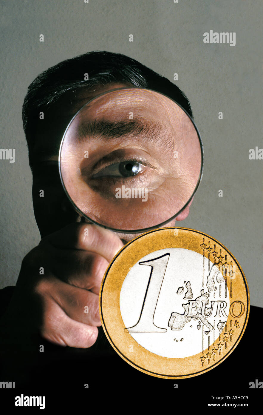 Mann, Blick durch die Lupe am Euro-Münze Stockfoto