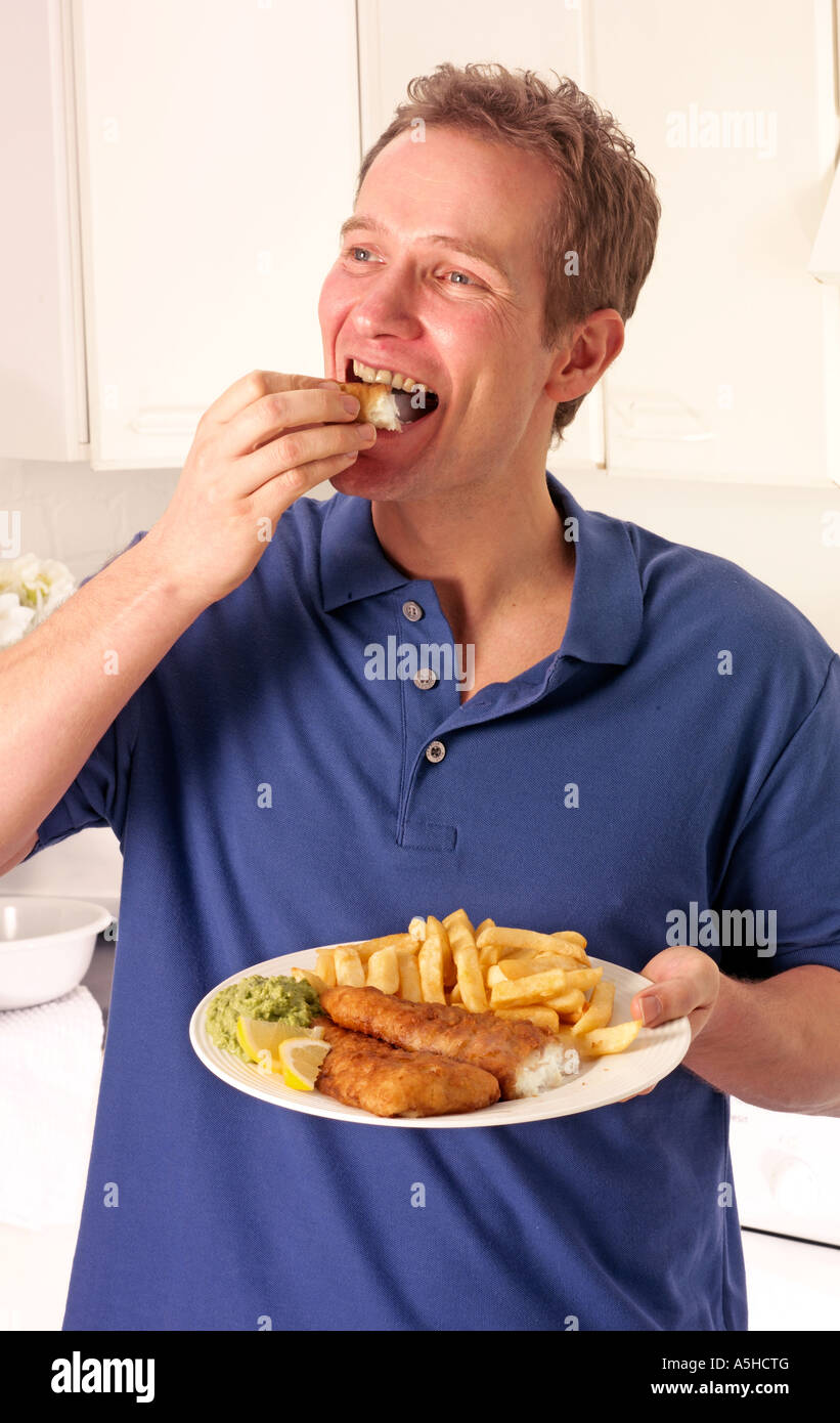 MANN IN DER KÜCHE ESSEN ANGELN UND CHIPS Stockfoto