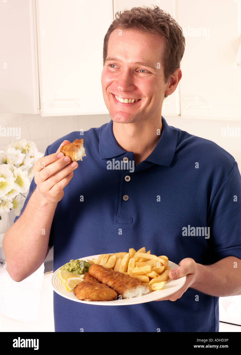 MANN IN DER KÜCHE ESSEN ANGELN UND CHIPS Stockfoto