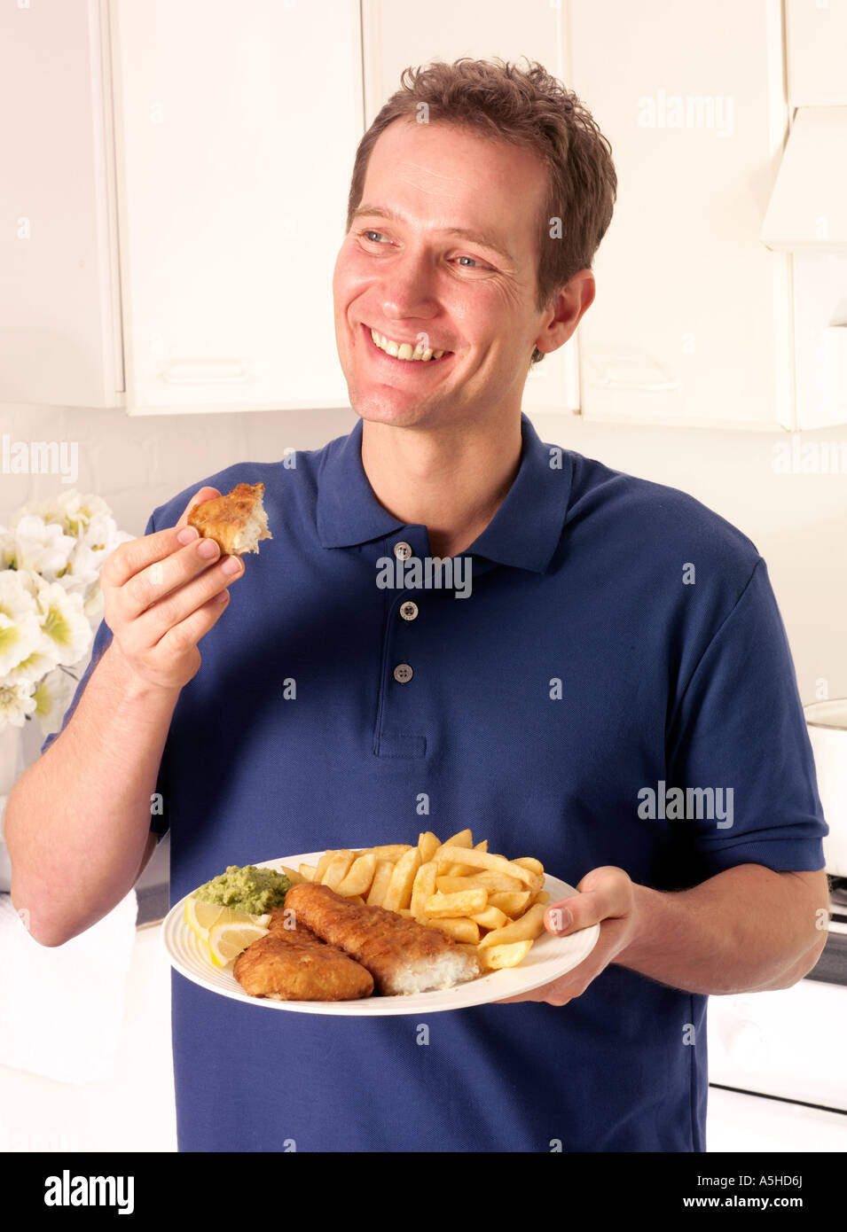 MANN IN DER KÜCHE ESSEN ANGELN UND CHIPS Stockfoto