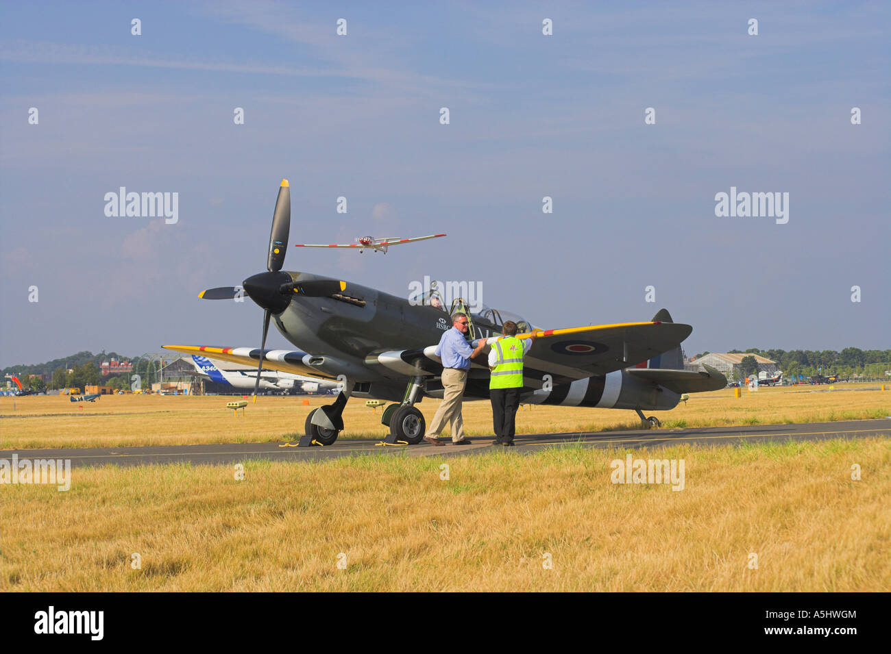 Grace Spitfire ML407 chocked wartet auf Taxi Clearance, während das Segelflugzeug Fox über Farnborough 2006 fliegt Stockfoto