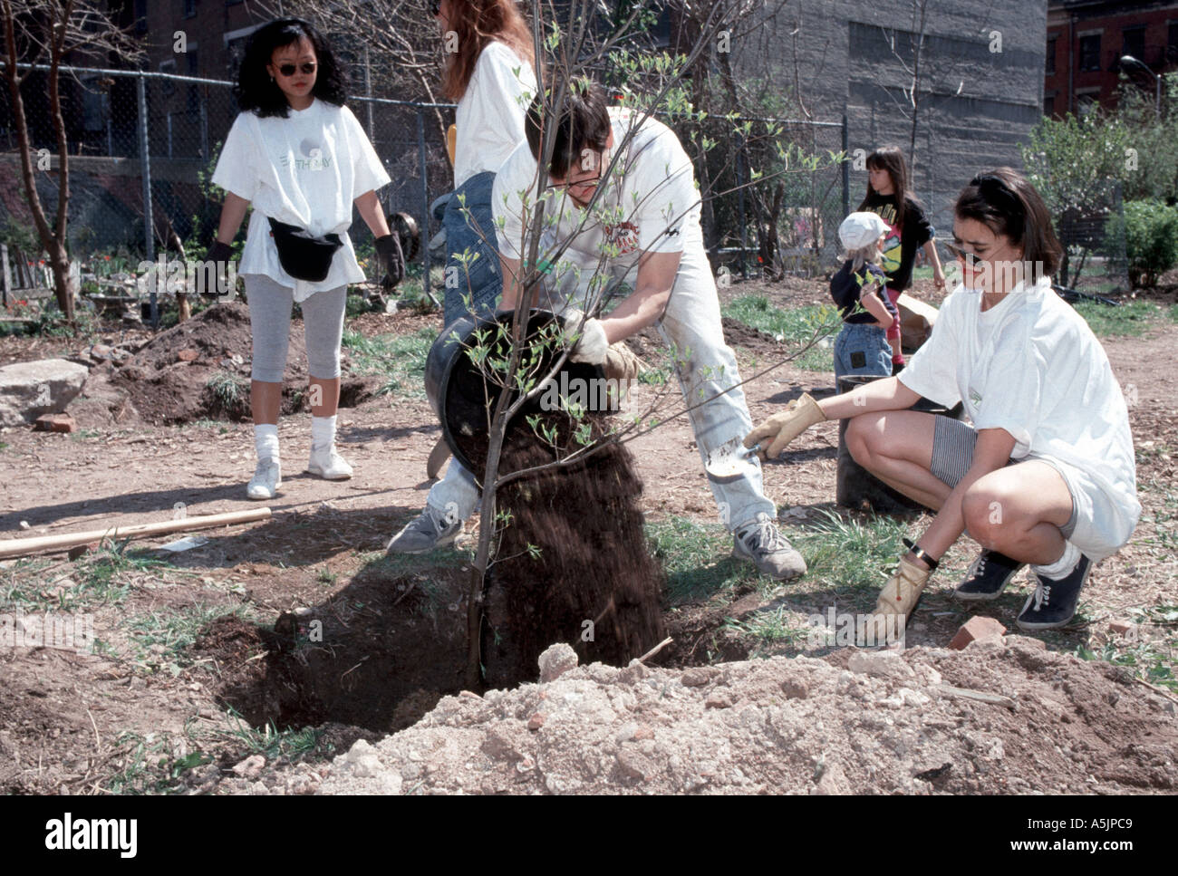 Freiwillige Pflanzen Bäume in einem künftigen gemeinschaftlichen Garten auf der Lower East Side von New York am Earth Day Stockfoto
