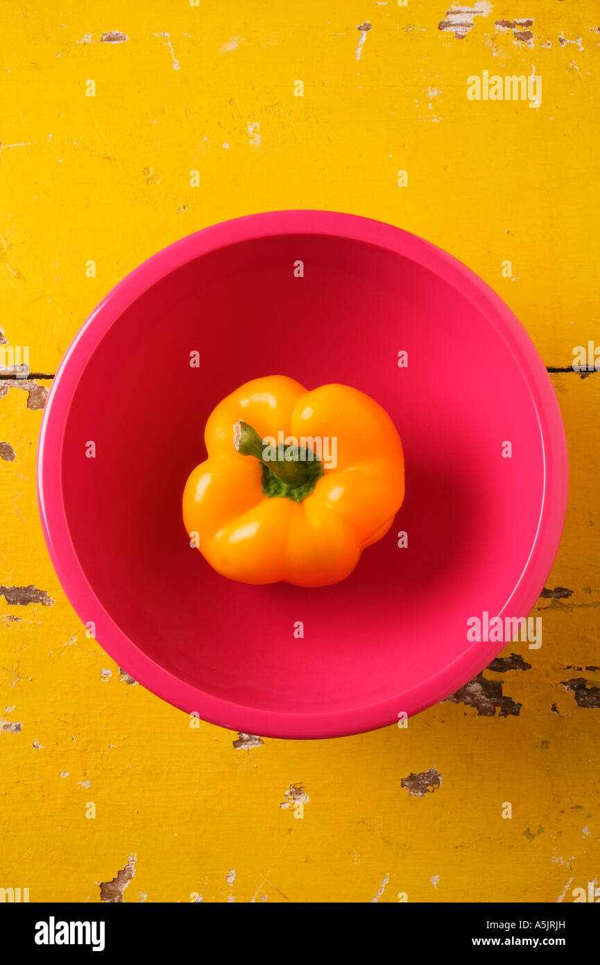 Rosa Schale mit gelber Paprika auf gelbe Tisch Stockfoto