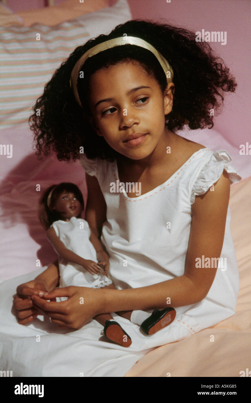 Kleine schwarze Mädchen spielen mit einer schwarzen Puppe - traurig, weil ihr Kindermädchen verlassen hat Stockfoto