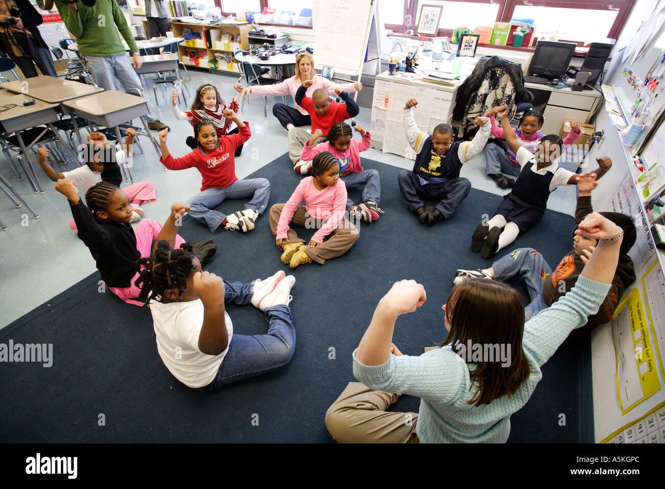 Schülerinnen und Schüler üben in ihrem Klassenzimmer für 15 Minuten pro Tag mit ihrem Lehrer in ein neues Programm zur Verbesserung der Gesundheit Stockfoto