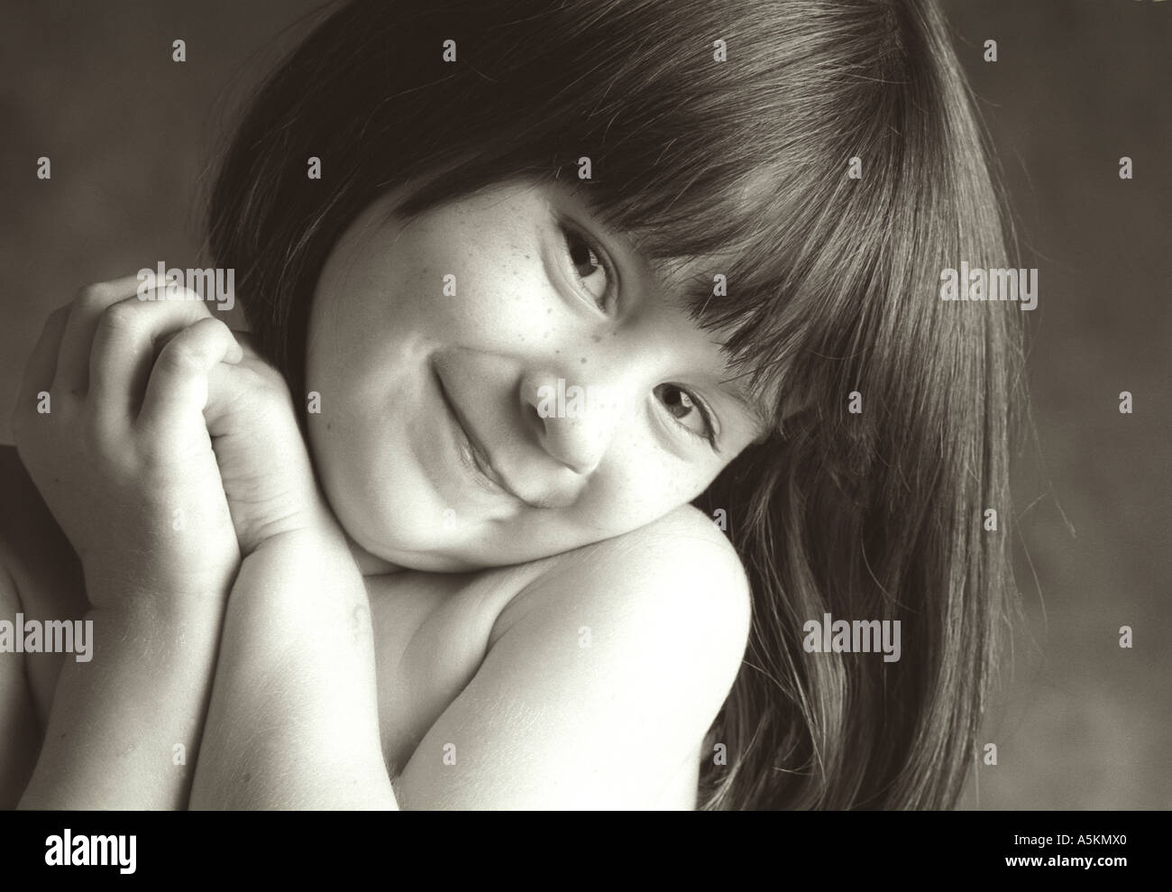 Ein junges Mädchen faltet ihre Hände und lächelt süß in diesem schwarz / weiß Foto. Stockfoto