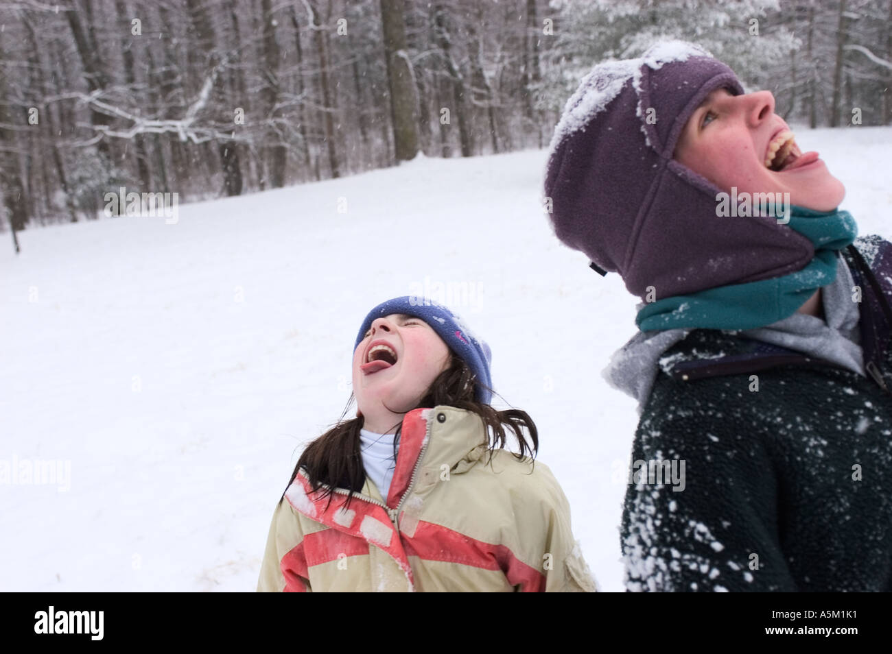 Zwei Mädchen fangen Schneeflocken mit ihren Zungen an einem Wintertag in Asheville, North Carolina Stockfoto