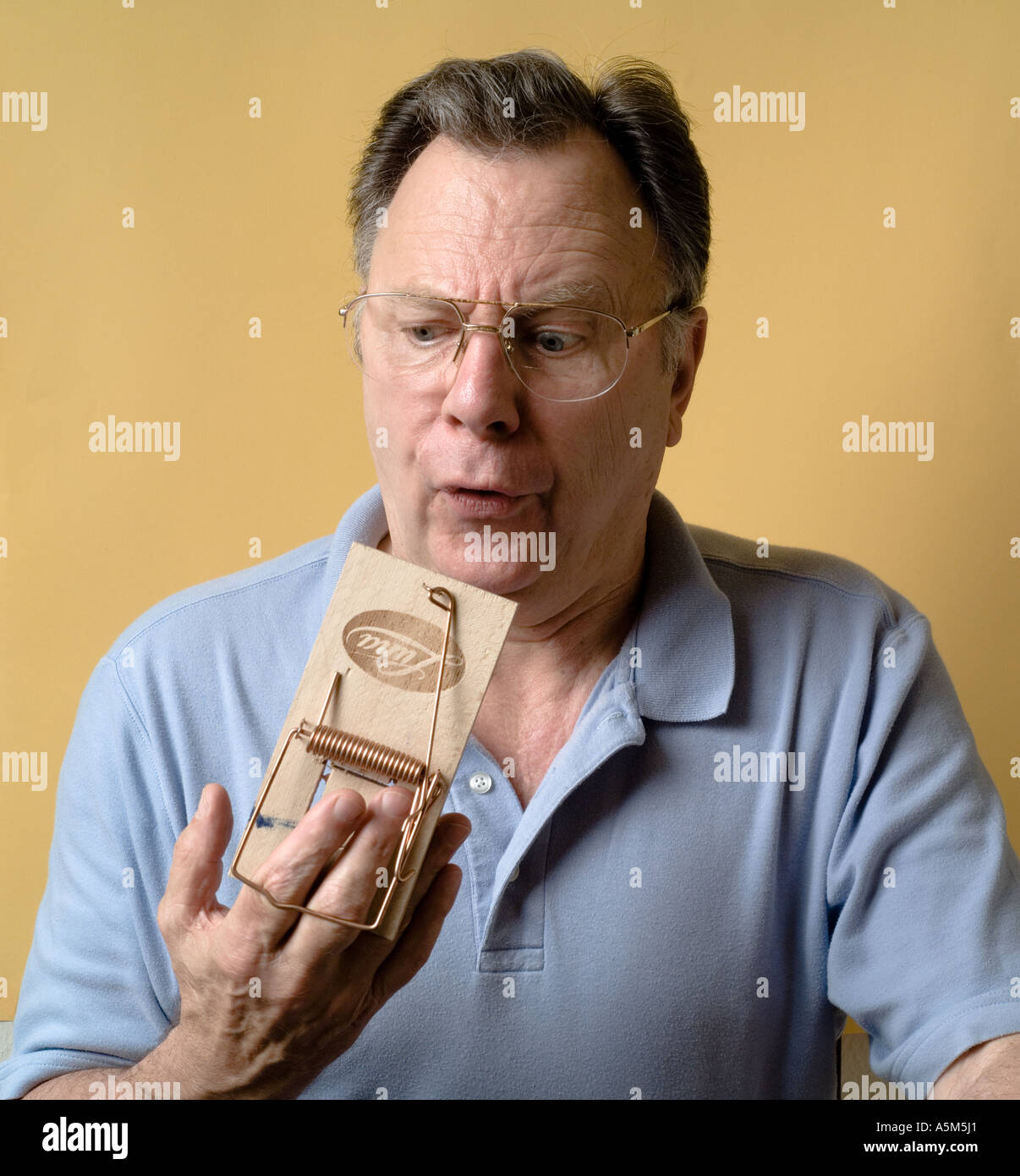 HERR MANN MIT SEINEN FINGERN IN EINE MAUSEFALLE Stockfoto